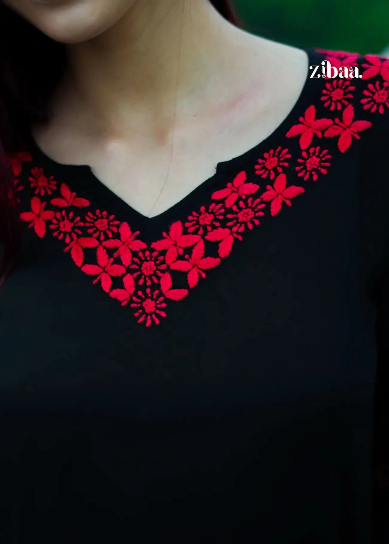 Black garment with red floral embroidery and 'zibaa' branding.