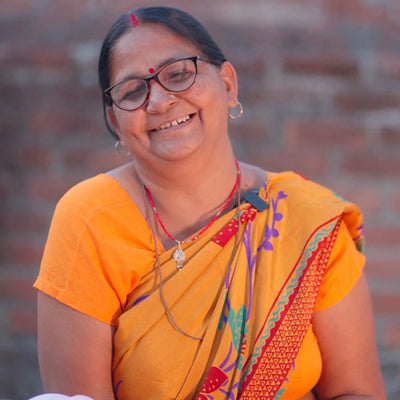 A Chikankari embroiderer wearing a yellow saree and smiling