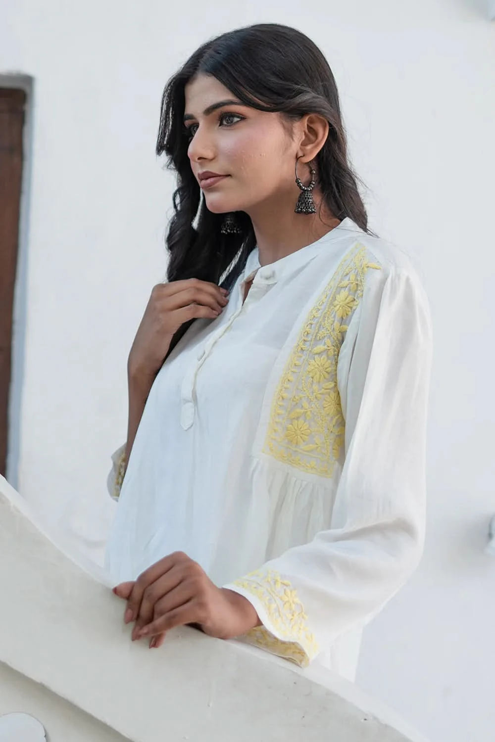 Woman wearing a white embroidered traditional outfit with a yellow design.