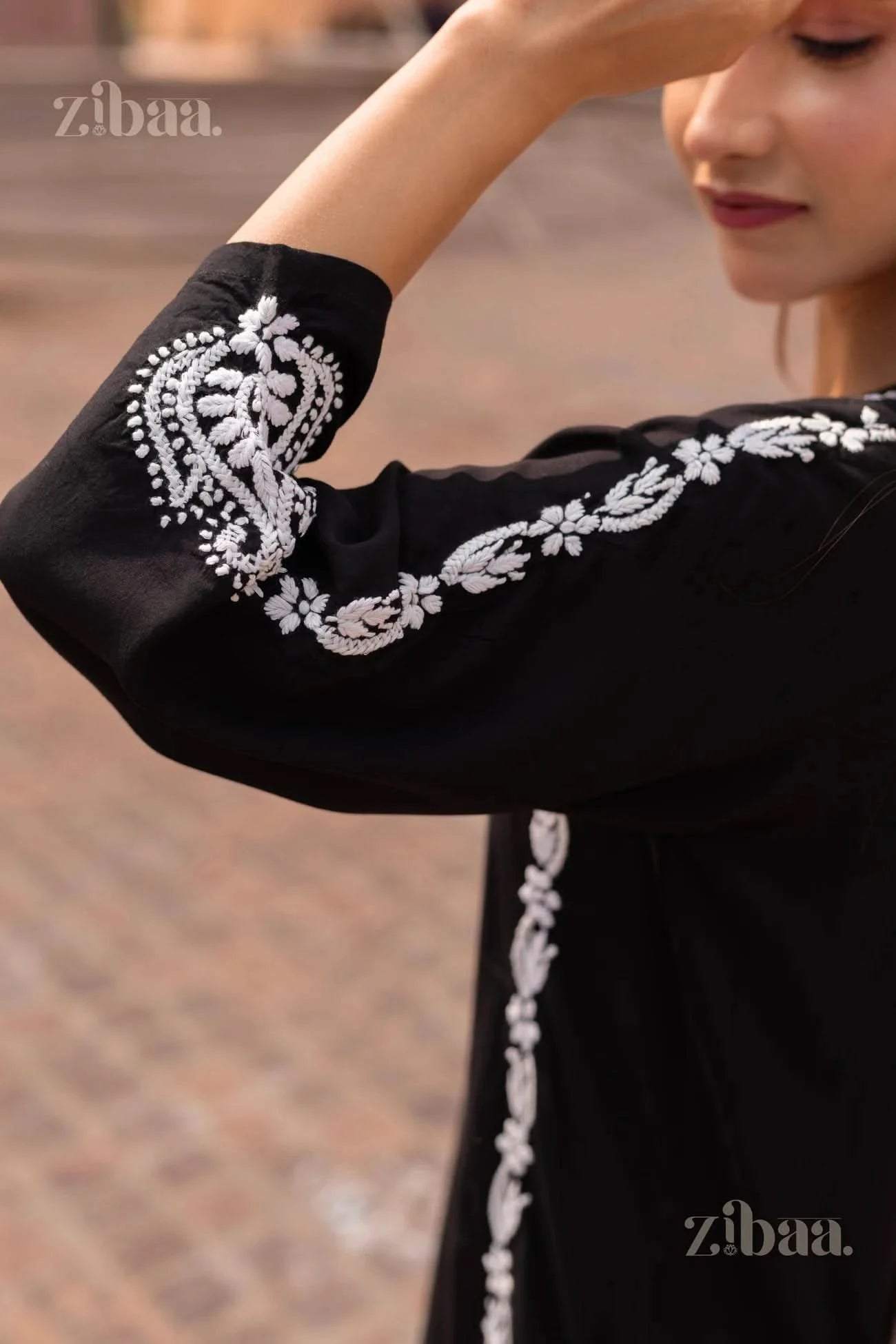 Close-up of a Black Kurti showing intricate white embroidery on the sleeve, highlighting traditional craftsmanship in an elegant style