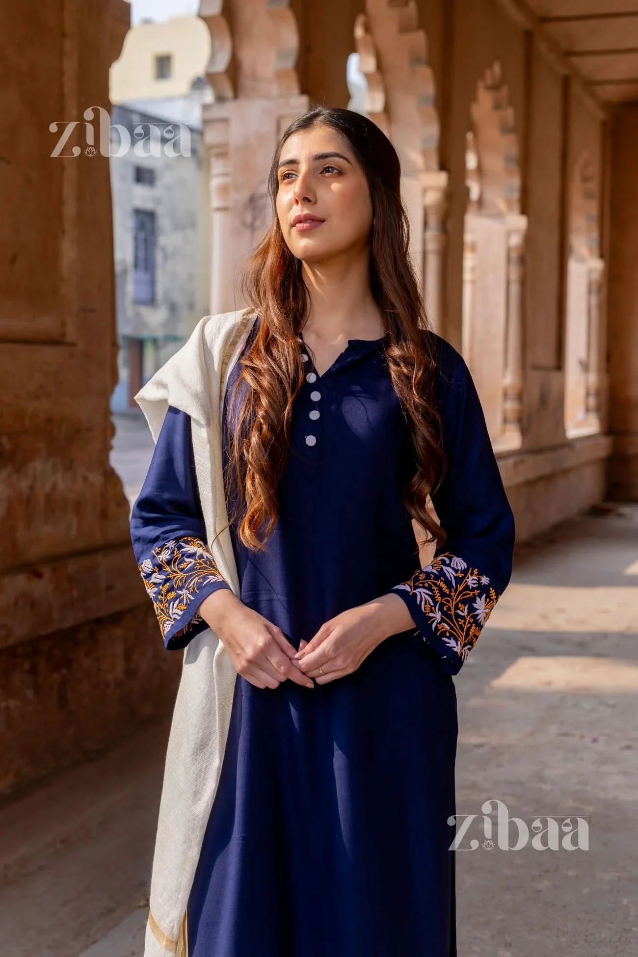 Woman wearing a traditional blue chikankari kurta set with floral embroidery and a white mulmul dupatta.