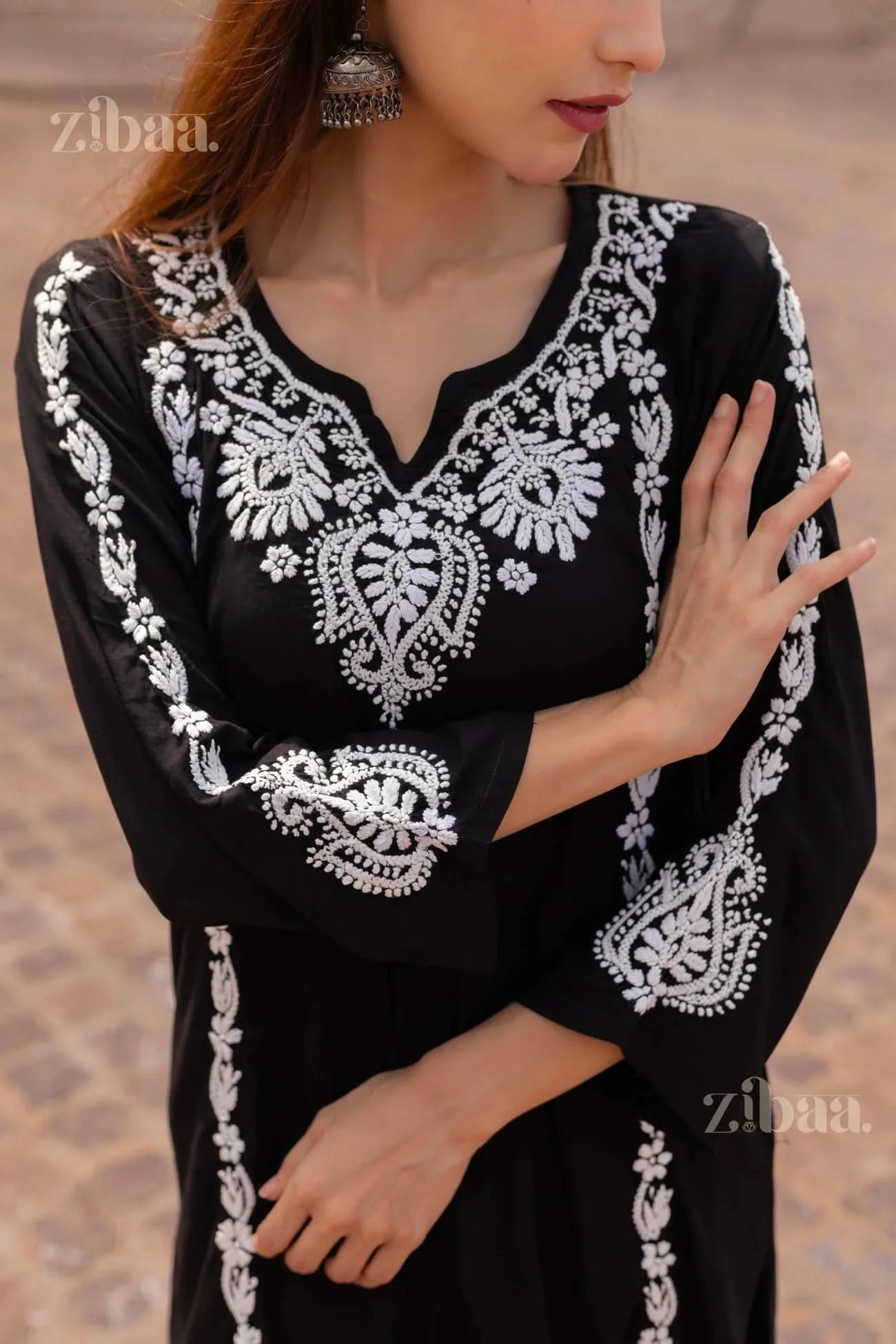 Close-up of a Black Chikankari Kurti featuring intricate white embroidery on the neckline and sleeves, styled with statement earrings
