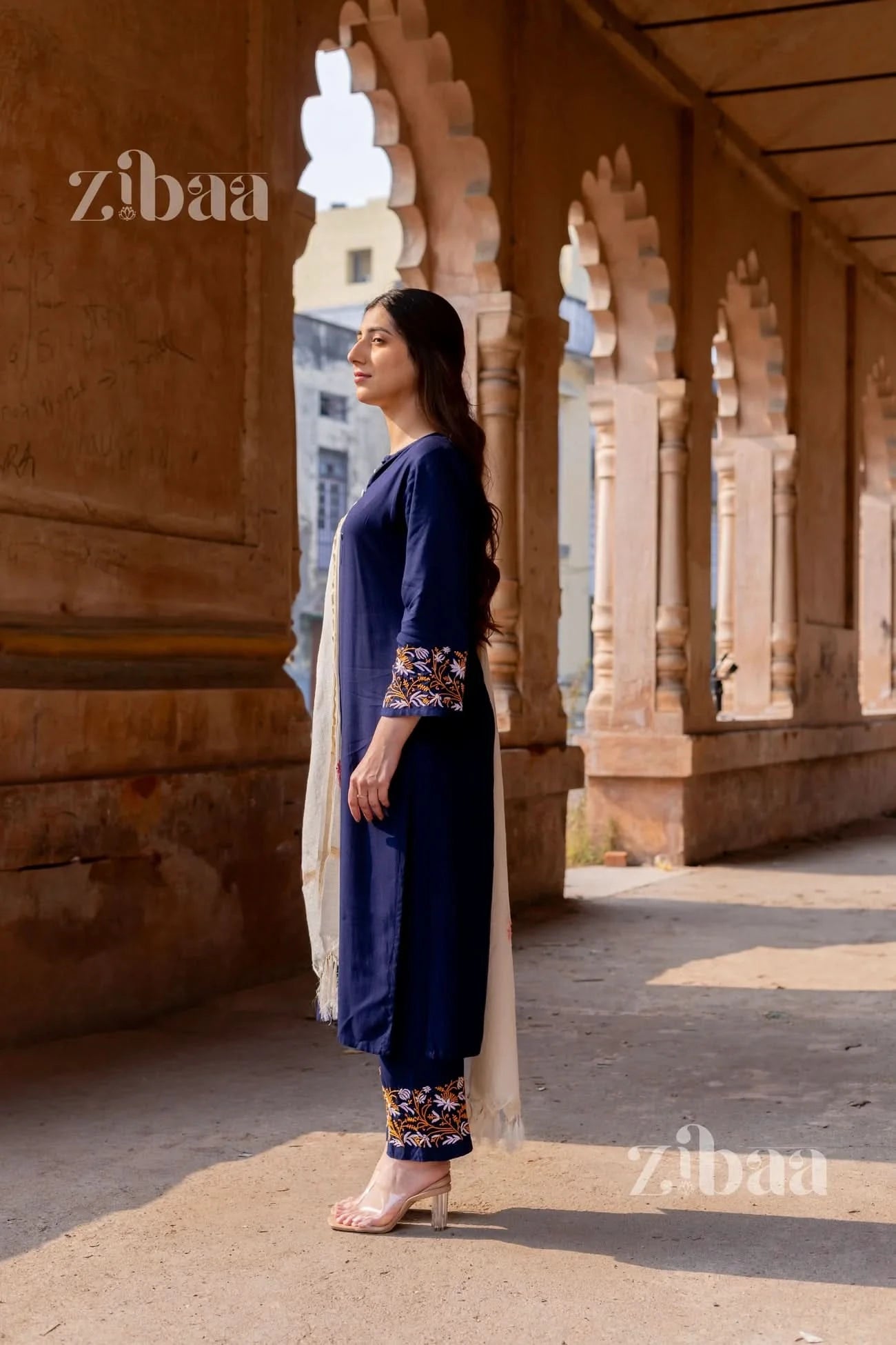 Traditional blue chikankari kurta set with floral threadwork worn by a woman, styled with a white mulmul dupatta.