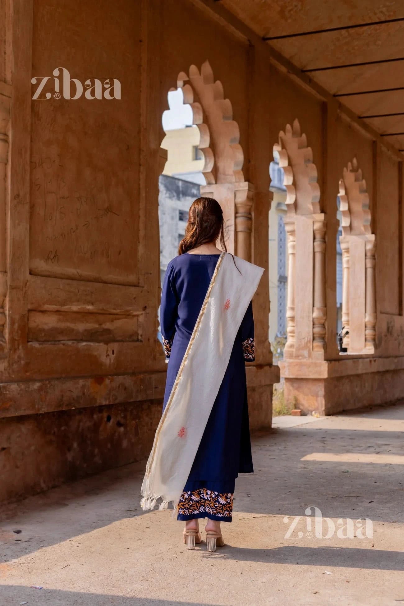 Model captured from the back wearing a blue chikankari kurta set with a flowing white Kota dupatta.