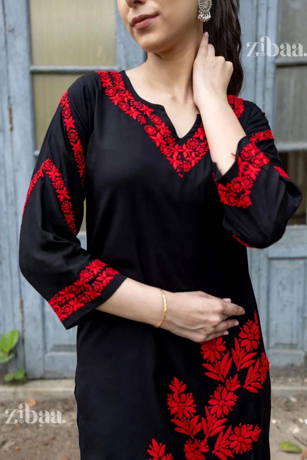 Black dress with red floral embroidery worn by a person, with 'zibaa' branding visible.