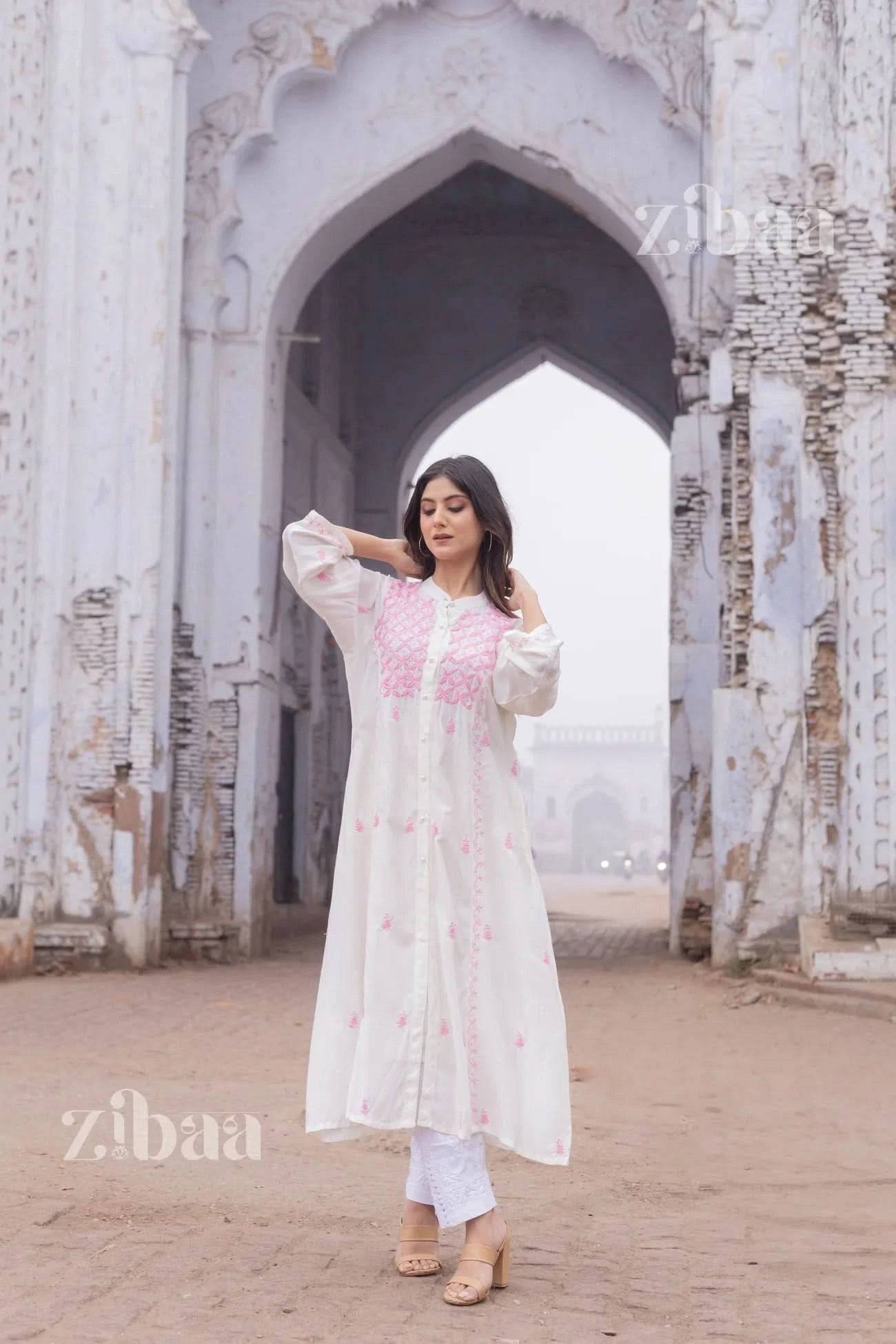 Graceful white chikankari kurta with geometric pink accents, worn outdoors in a natural environment.