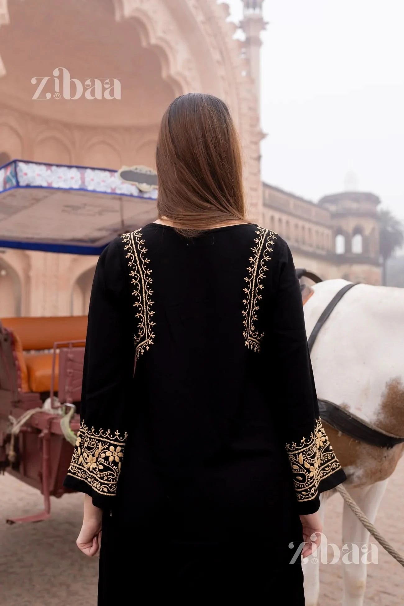 Back view of woman wearing black chikankari kurti standing outside an architectural backdrop.