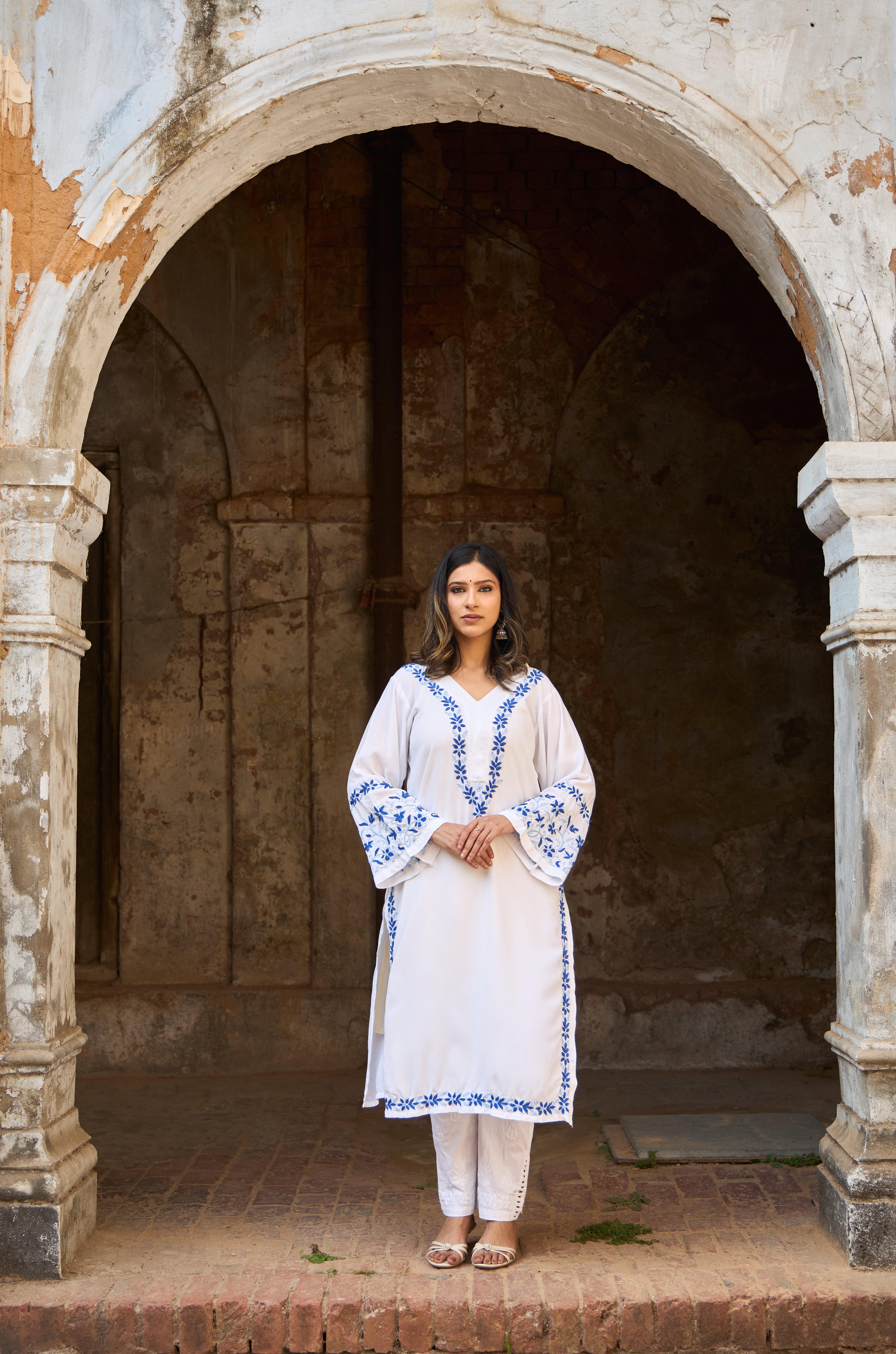 Woman in a White Chikankari Kurta standing in an archway of an old building