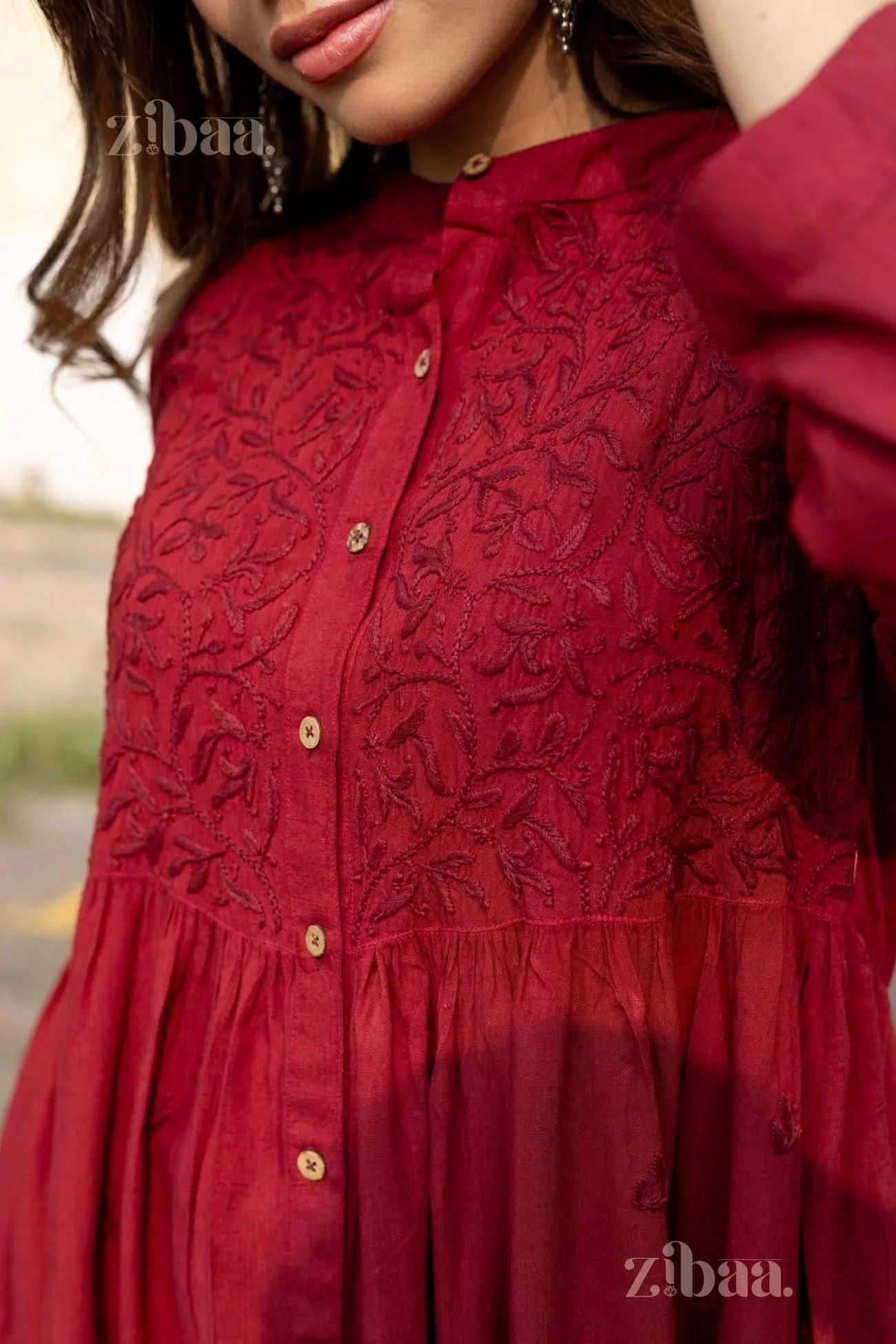 A close-up of a woman slightly tilting her head, showcasing the embroidery and button-down design of a Chikankari top for women.