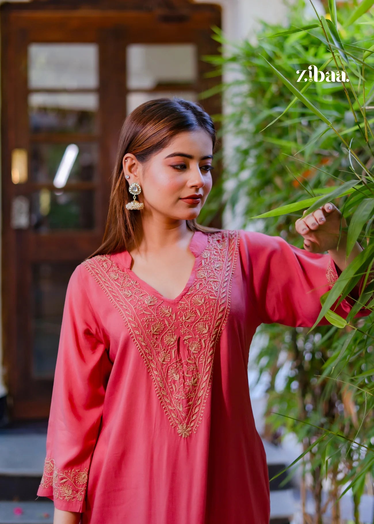 The model stands confidently in a coral chikankari kurti, highlighting the detailed chikankari stitching.