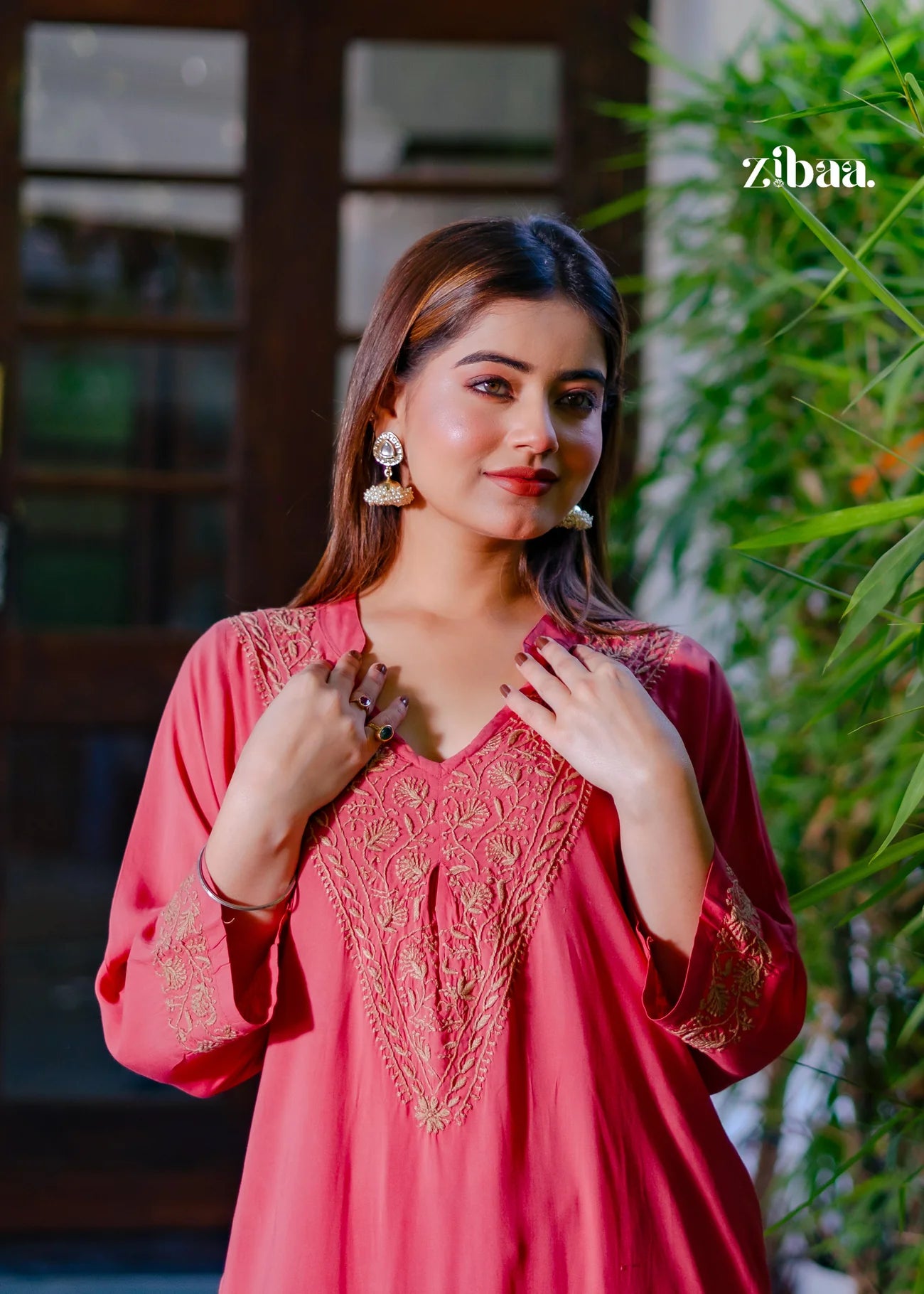 The model poses in a coral chikankari kurti, beautifully showcasing the fine chikankari stitching.