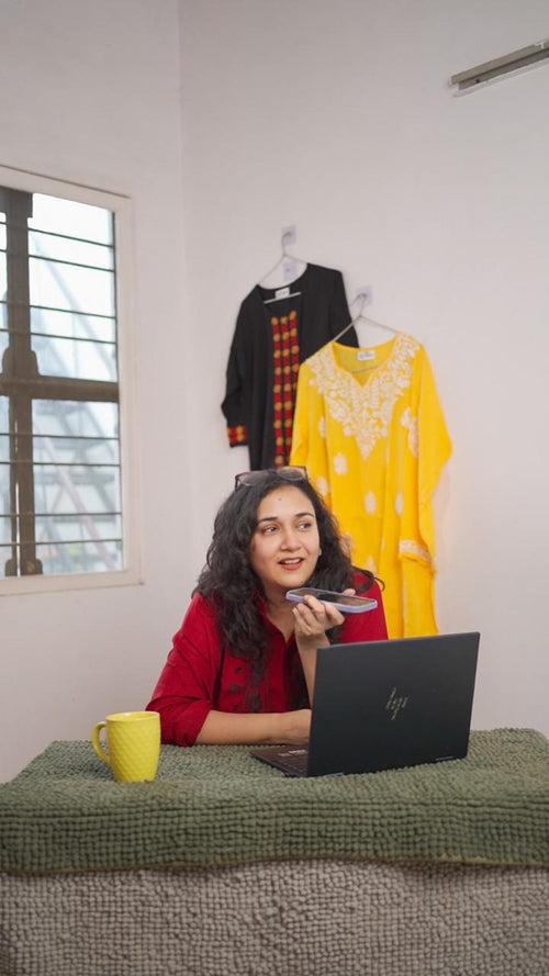 Image of a women wearing a red Chikanakri shirt speaking on phone
