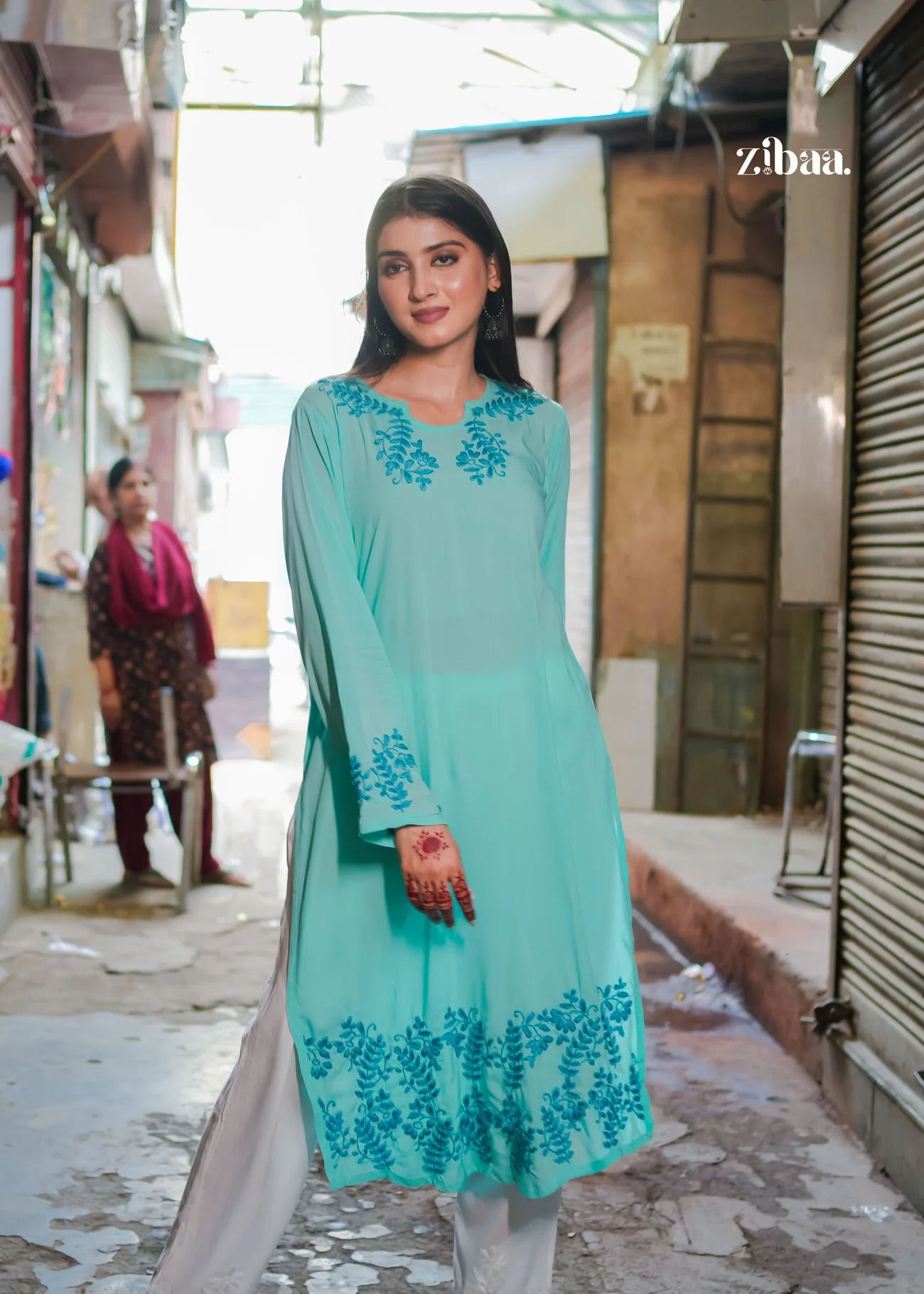 A woman stands on the street wearing a blue chikankari kurti featuring detailed and intricate embroidery, showcasing the fine craftsmanship of the fabric