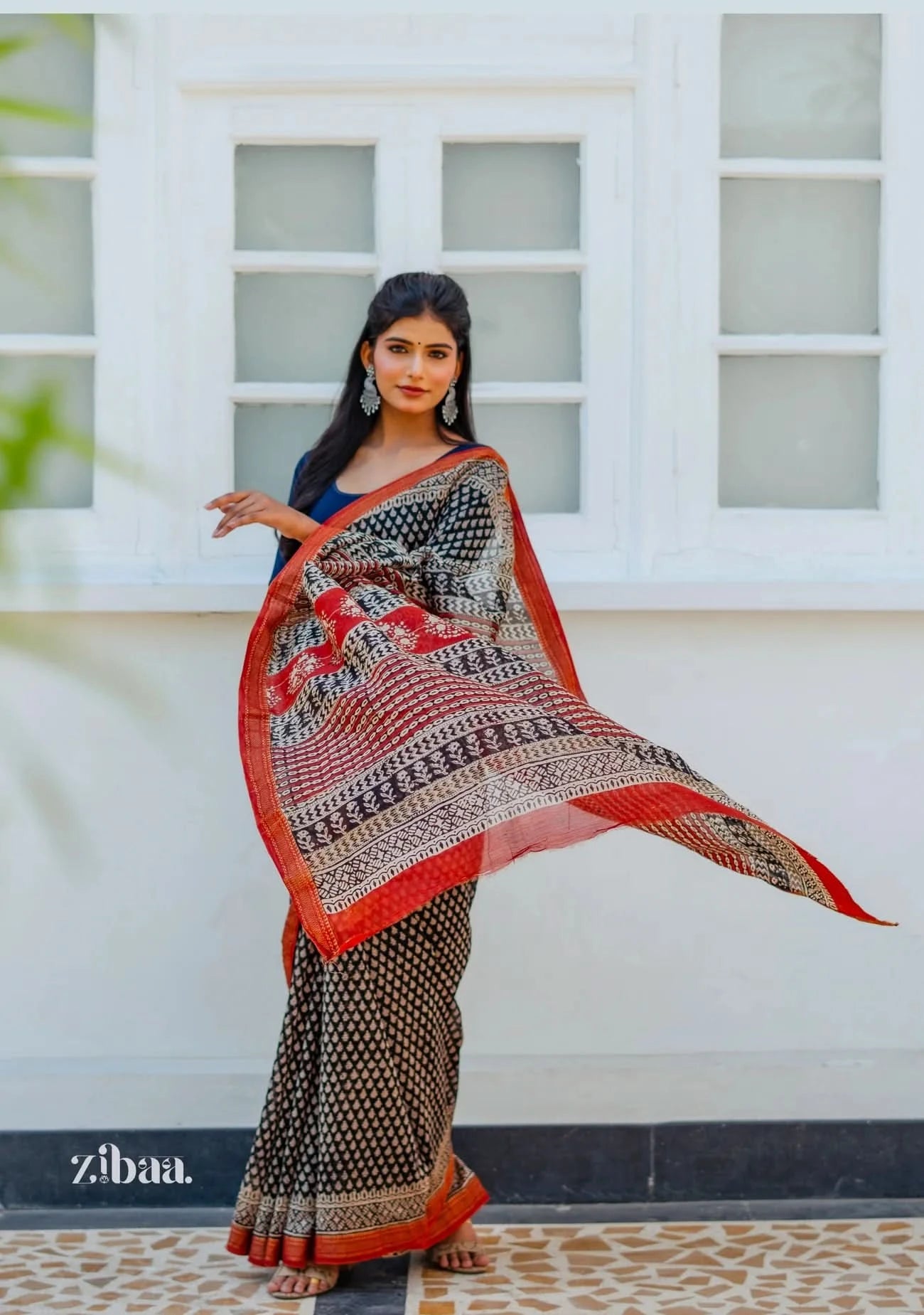 Woman wearing a patterned saree in front of a white window