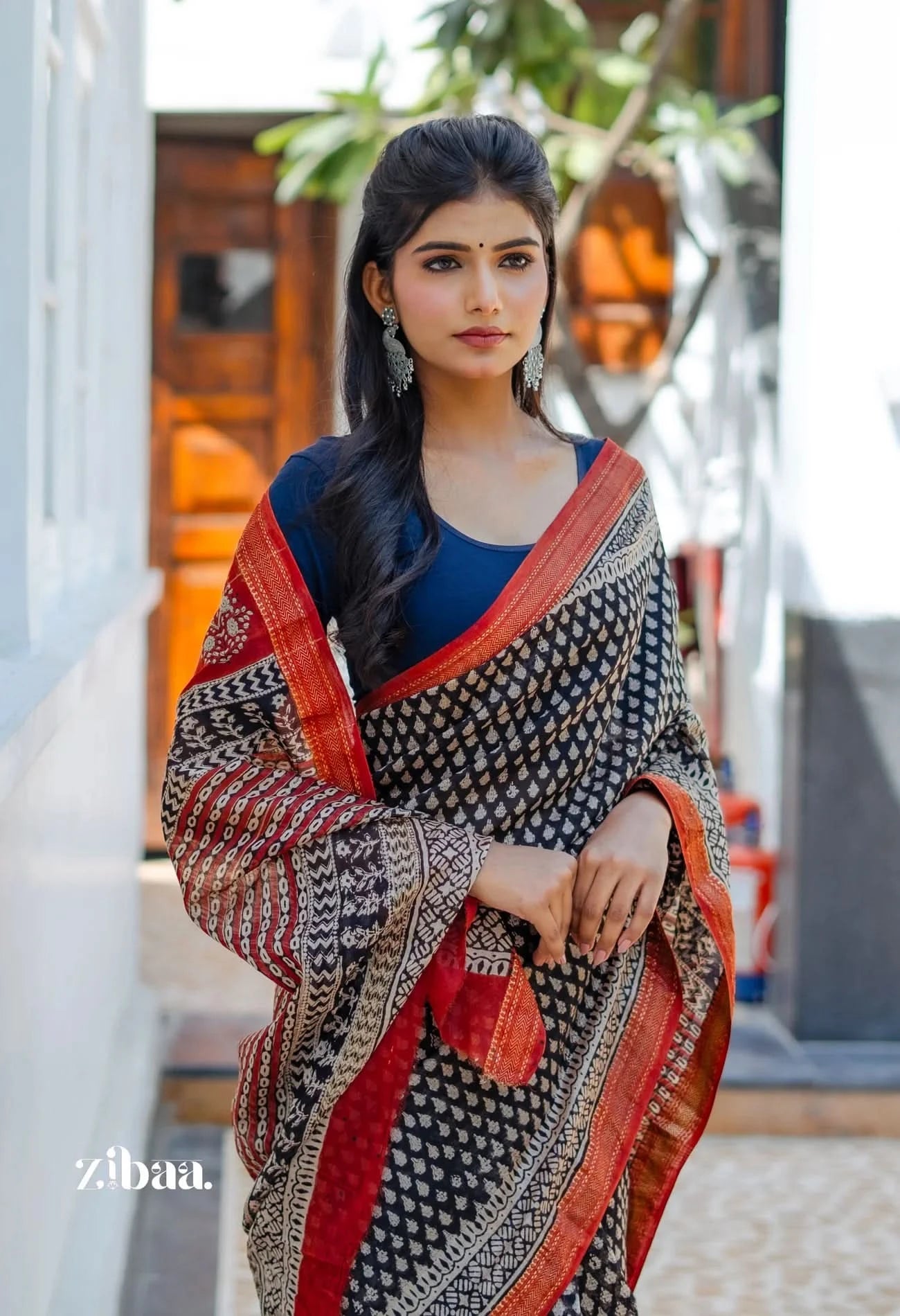 Woman wearing a traditional saree with a blue blouse in an outdoor setting.