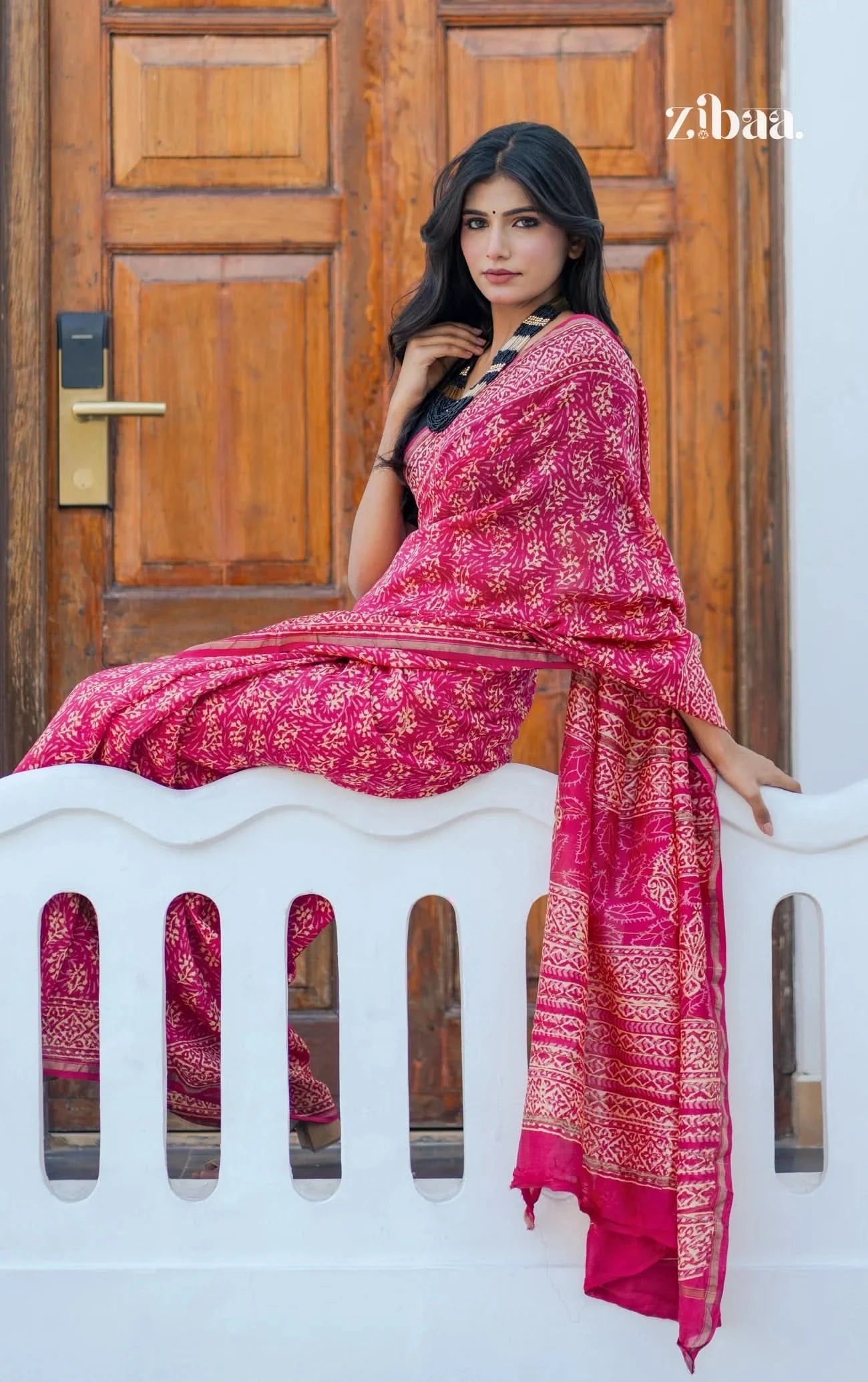 Woman wearing a pink saree with a zibaa label in the corner.