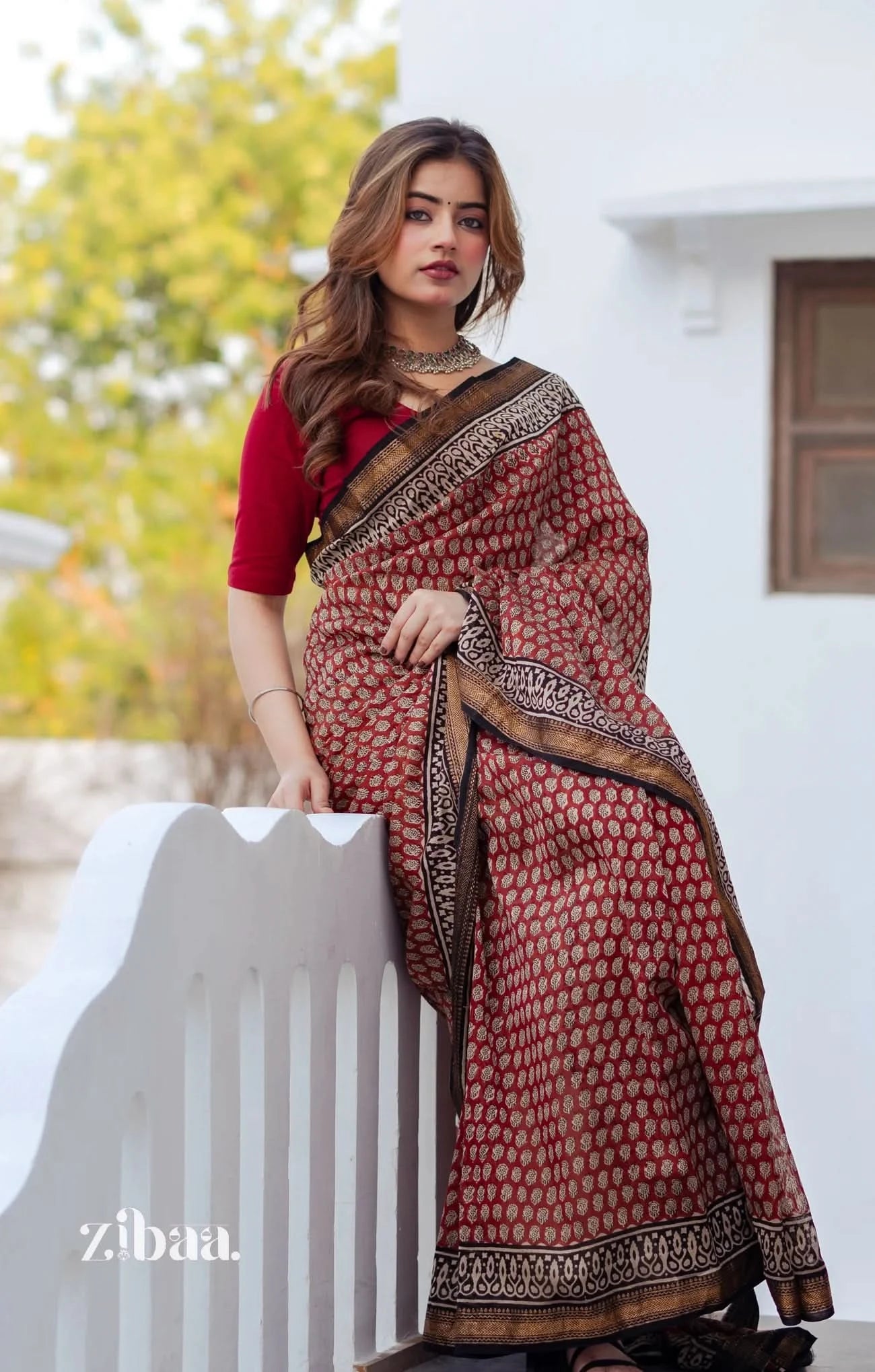 Woman wearing a red and brown saree with a white background