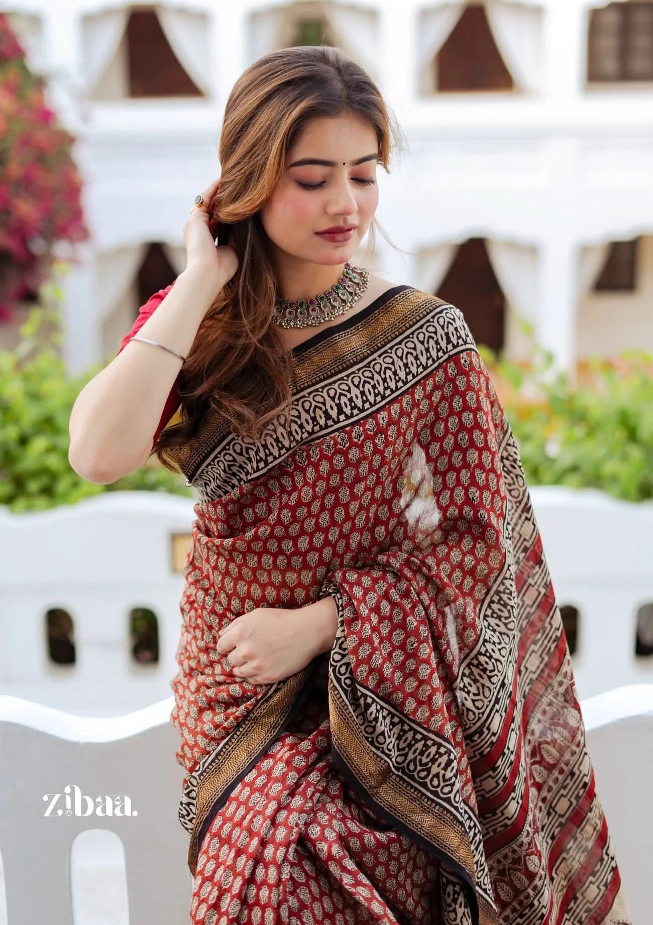 Woman wearing a red and gold saree with a white background
