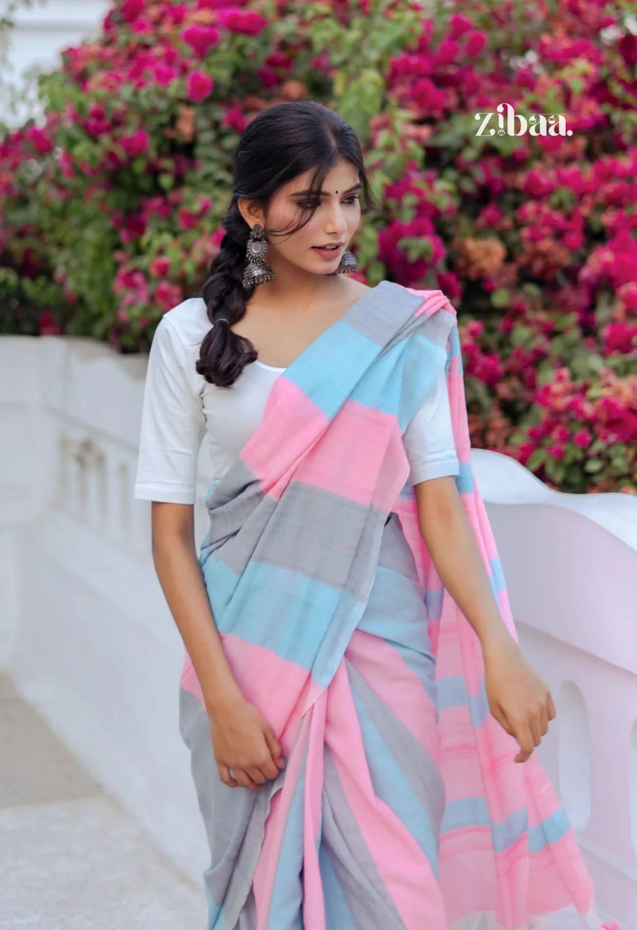 Woman wearing a colorful saree with a floral background, featuring the brand 'zibaa'.