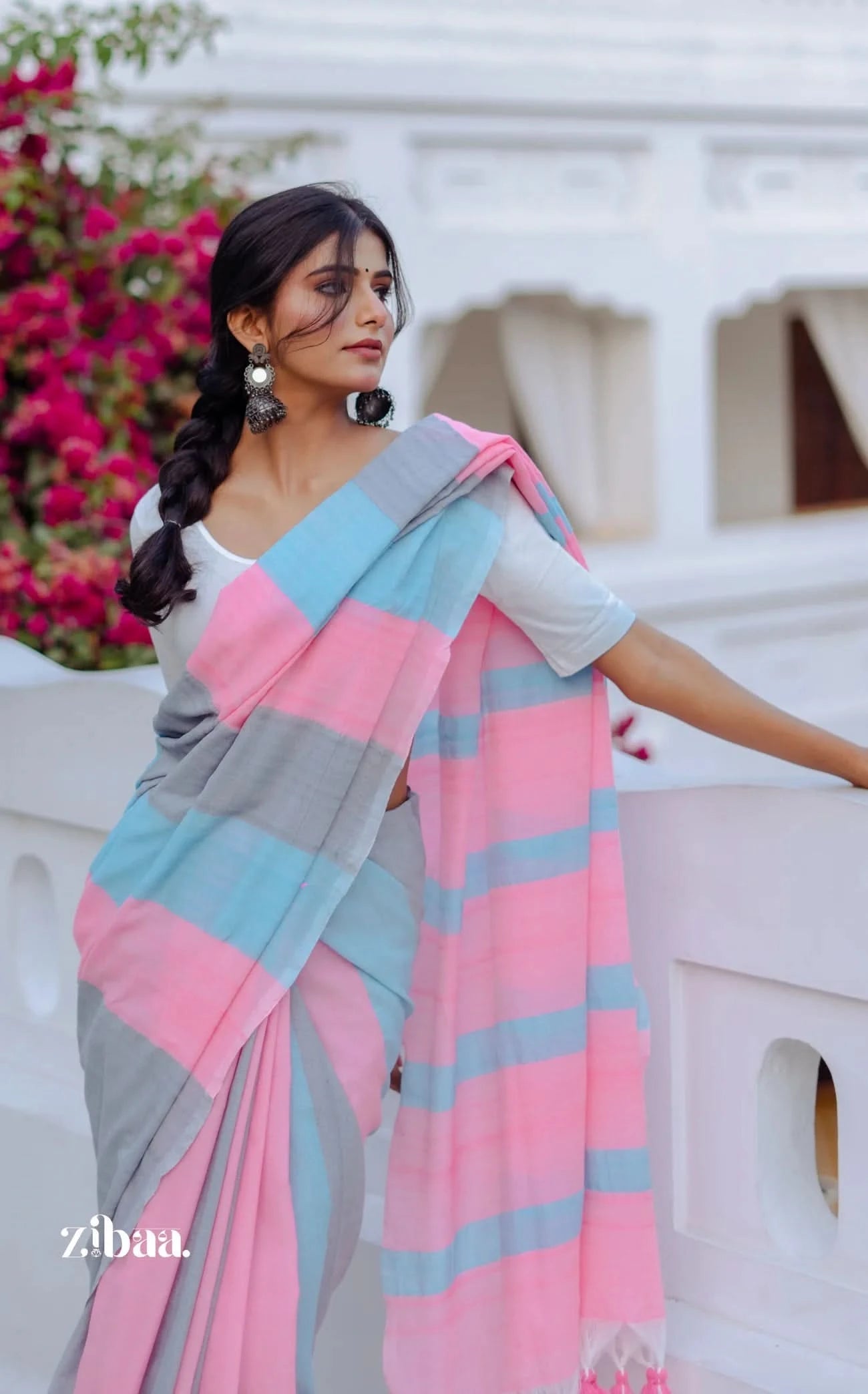 Woman wearing a colorful saree with a white background and floral decorations.