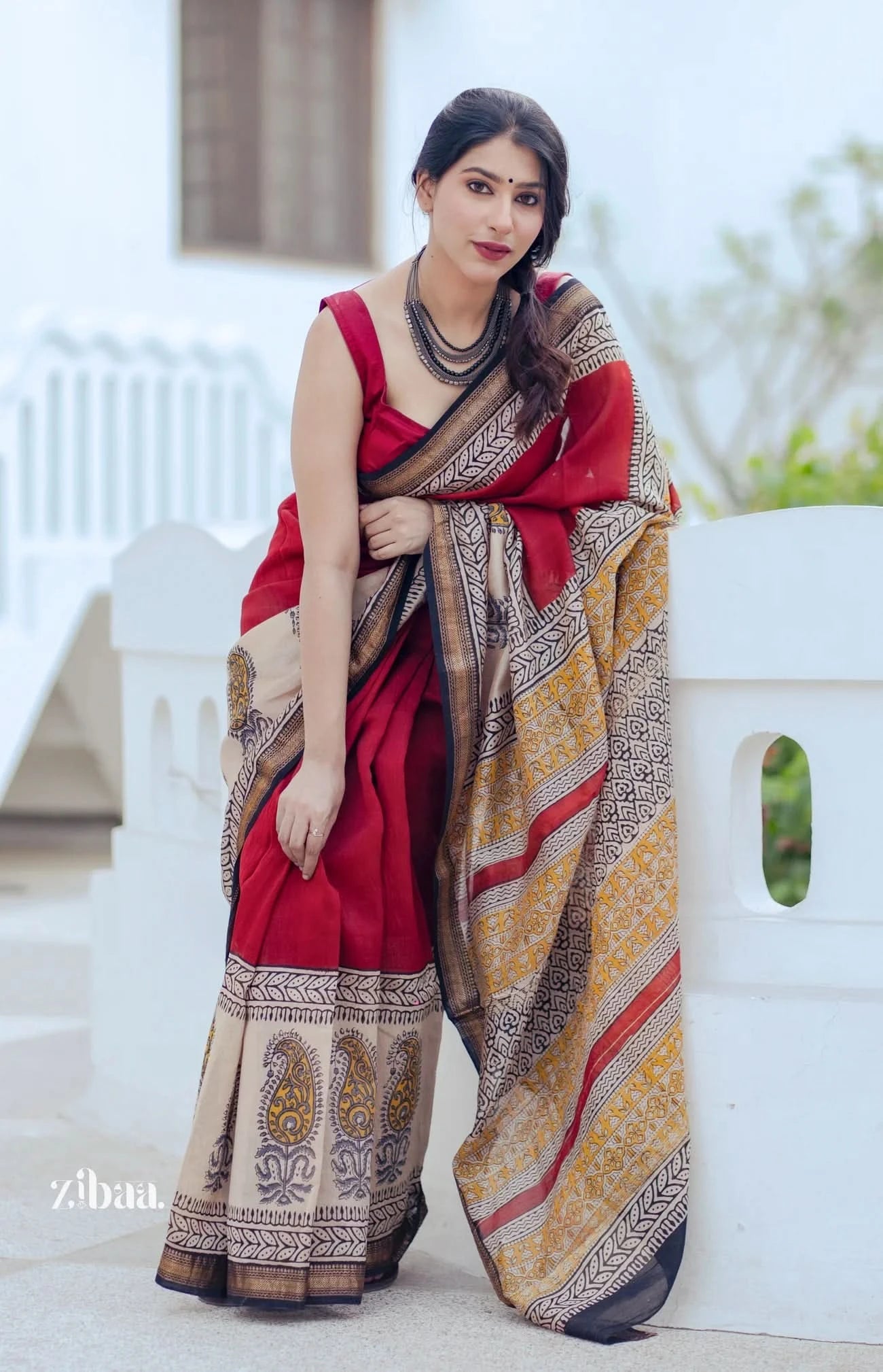 Woman wearing a red and gold saree with a white background
