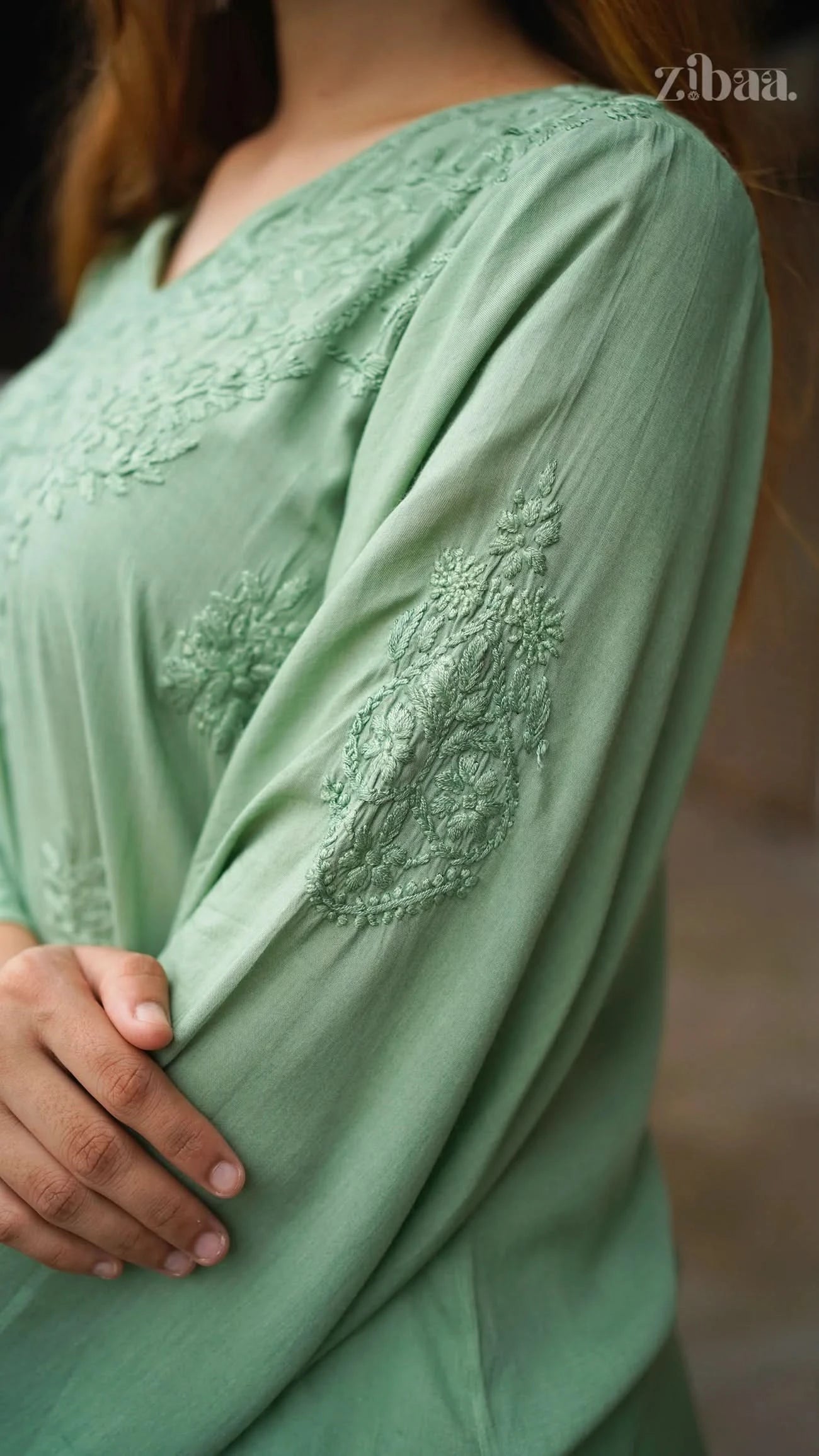 Green dress with intricate lace detailing on a blurred background