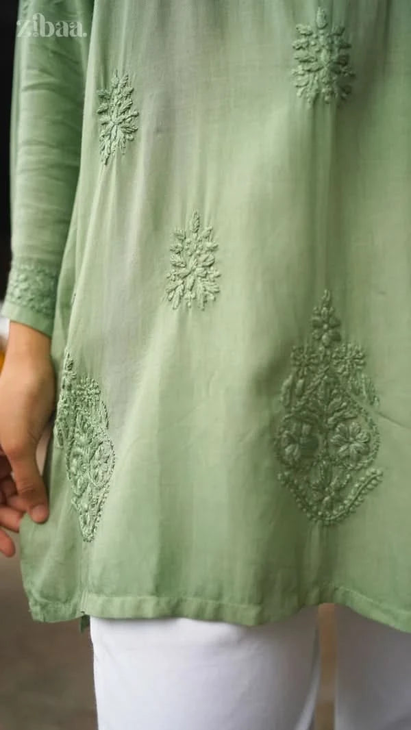Light green embroidered top worn by a person, with a focus on the intricate designs.