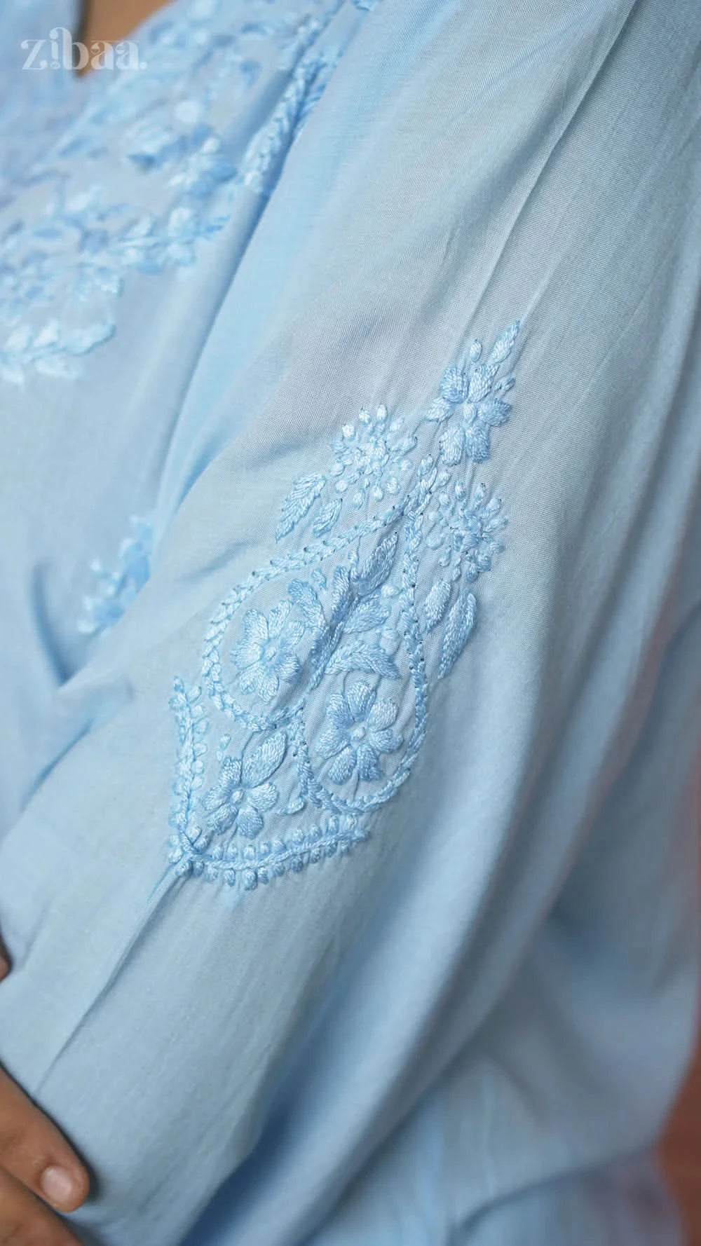 Close-up of a light blue embroidered garment with intricate detailing.