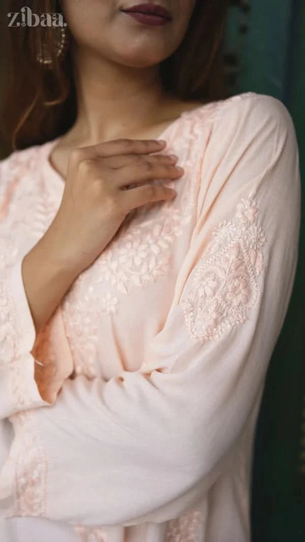 Close-up of a person wearing a light pink lace dress with a blurred background