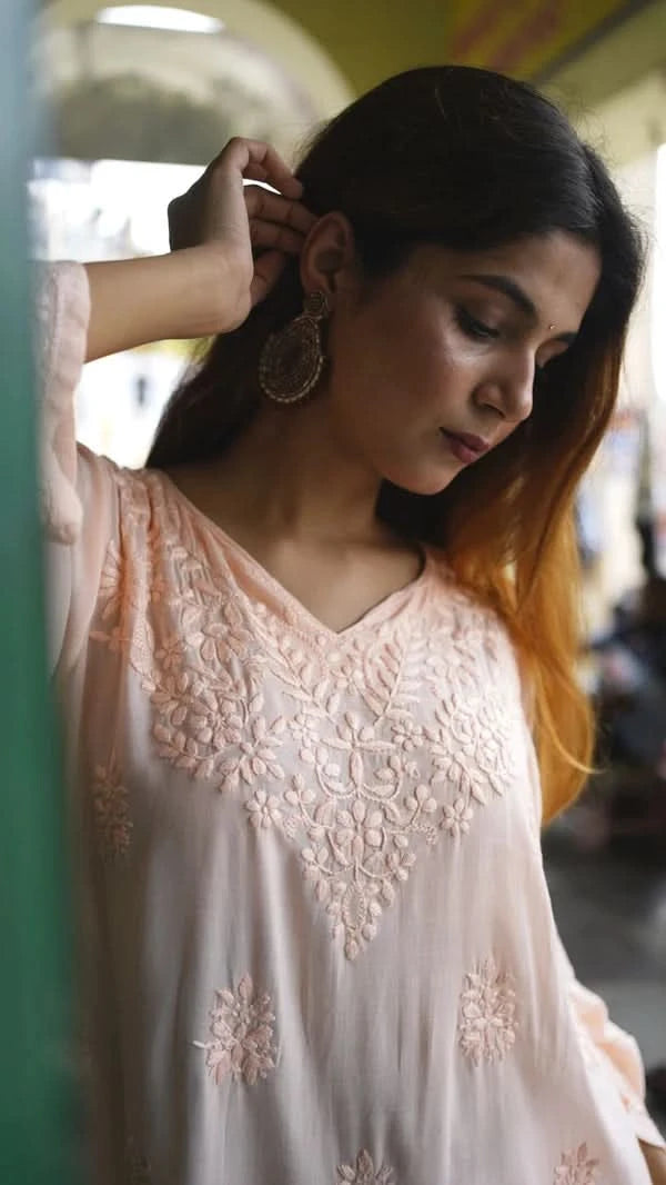 Woman adjusting an earring in a blurred indoor setting