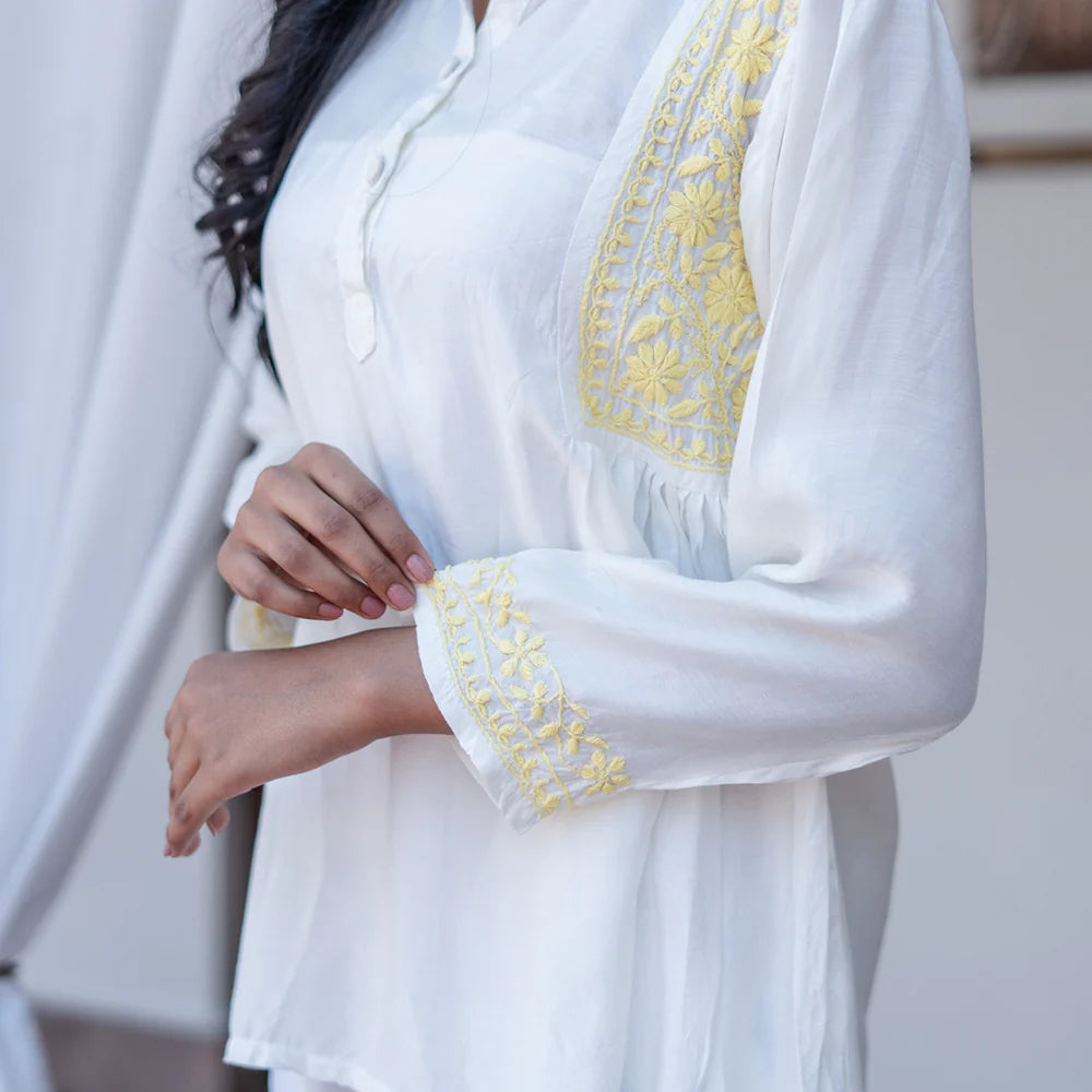 White blouse with yellow embroidery on a neutral background