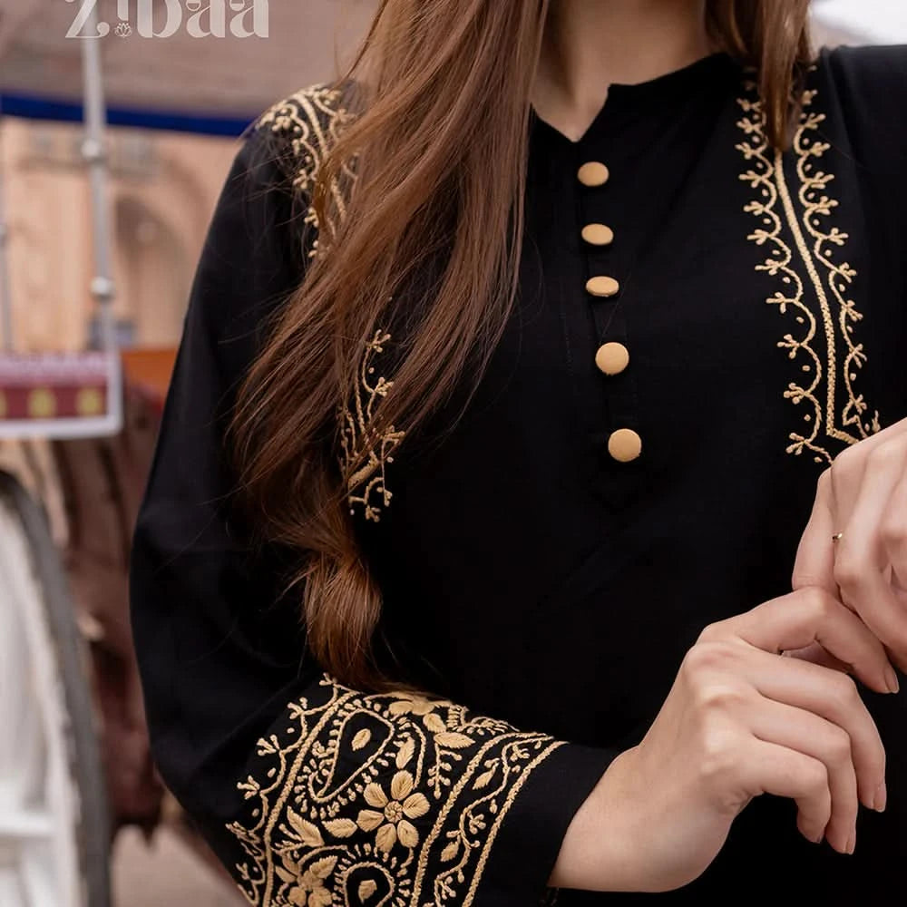 Black outfit with gold embroidery and buttons, blurred background