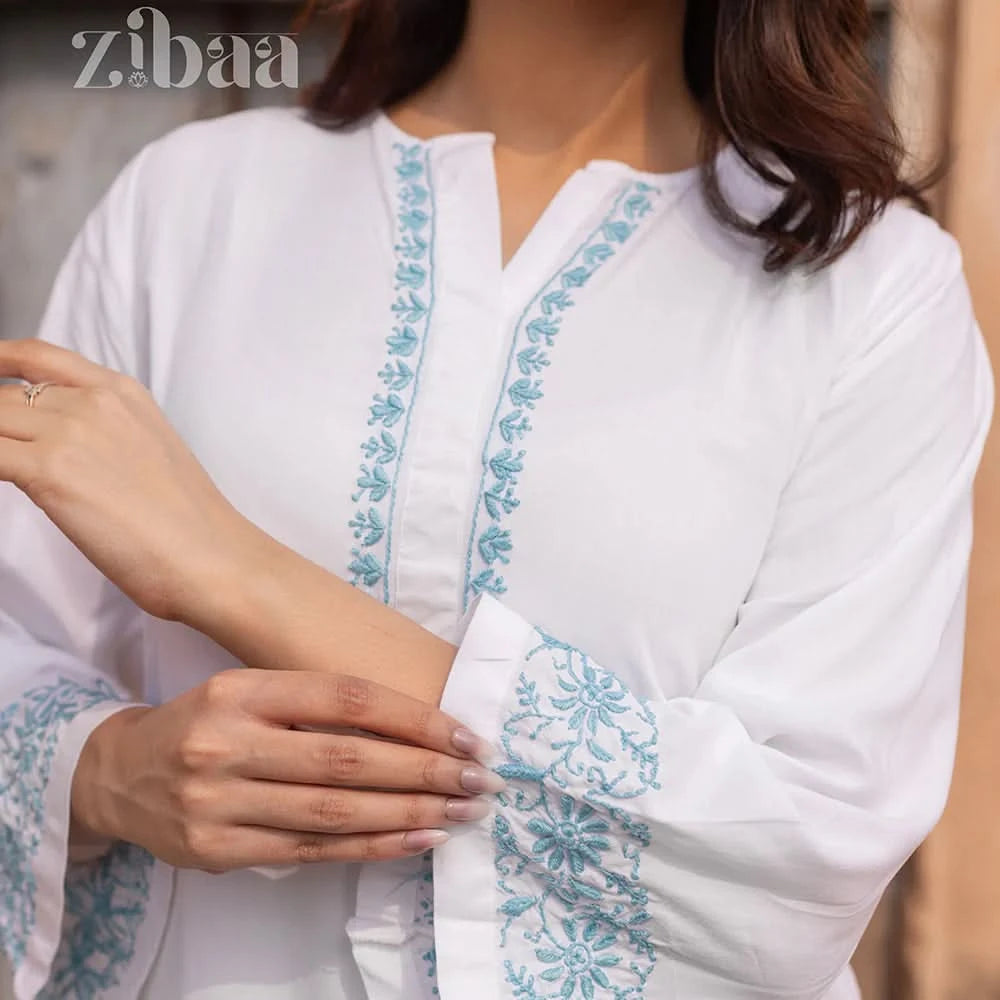 White garment with blue embroidery being worn by a person, brand 'zibaa' visible.