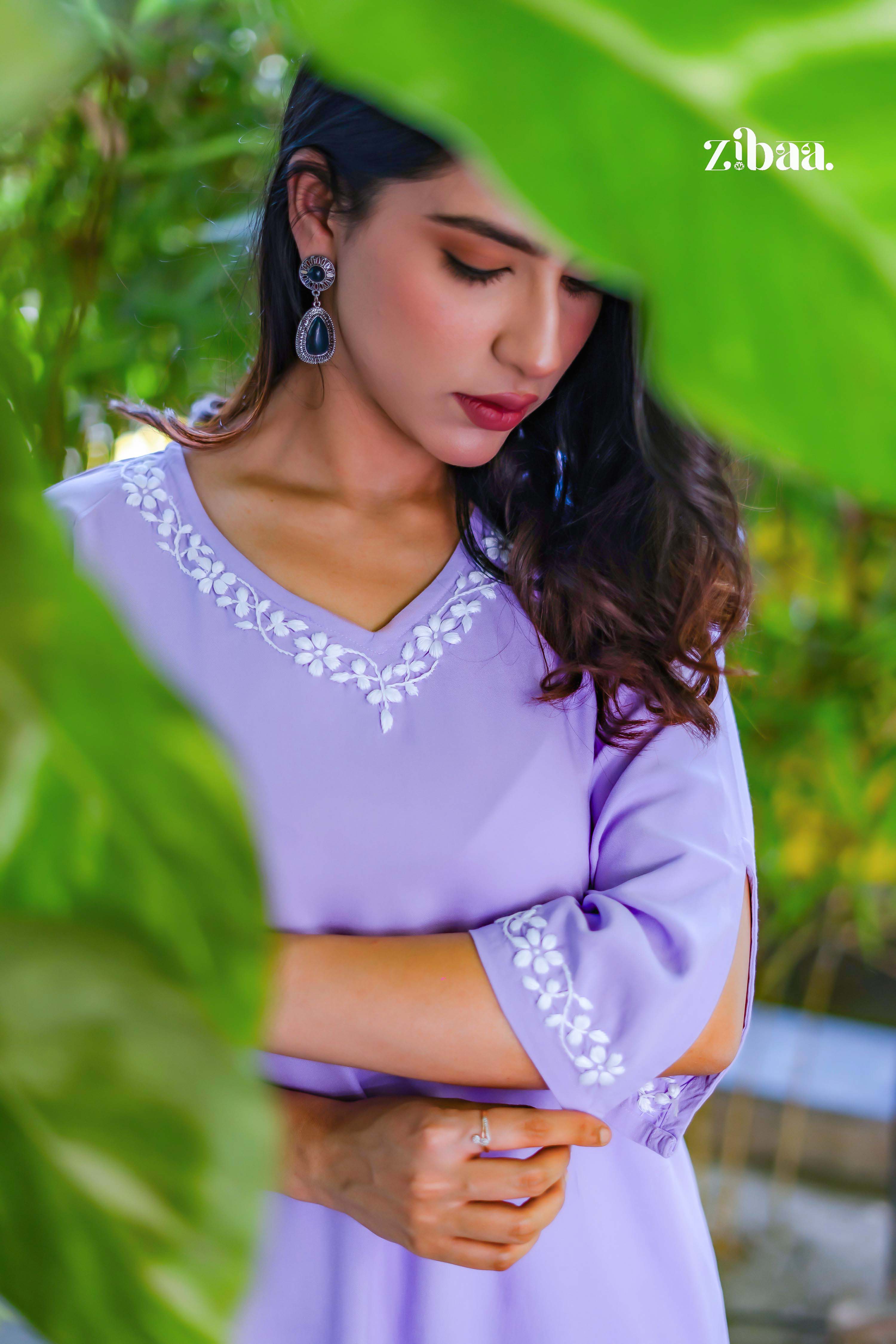 Model showing lavender kurta close-up with embroidered neckline. She folds her arm slightly, highlighting sleeve embroidery for a chic ethnic look. 