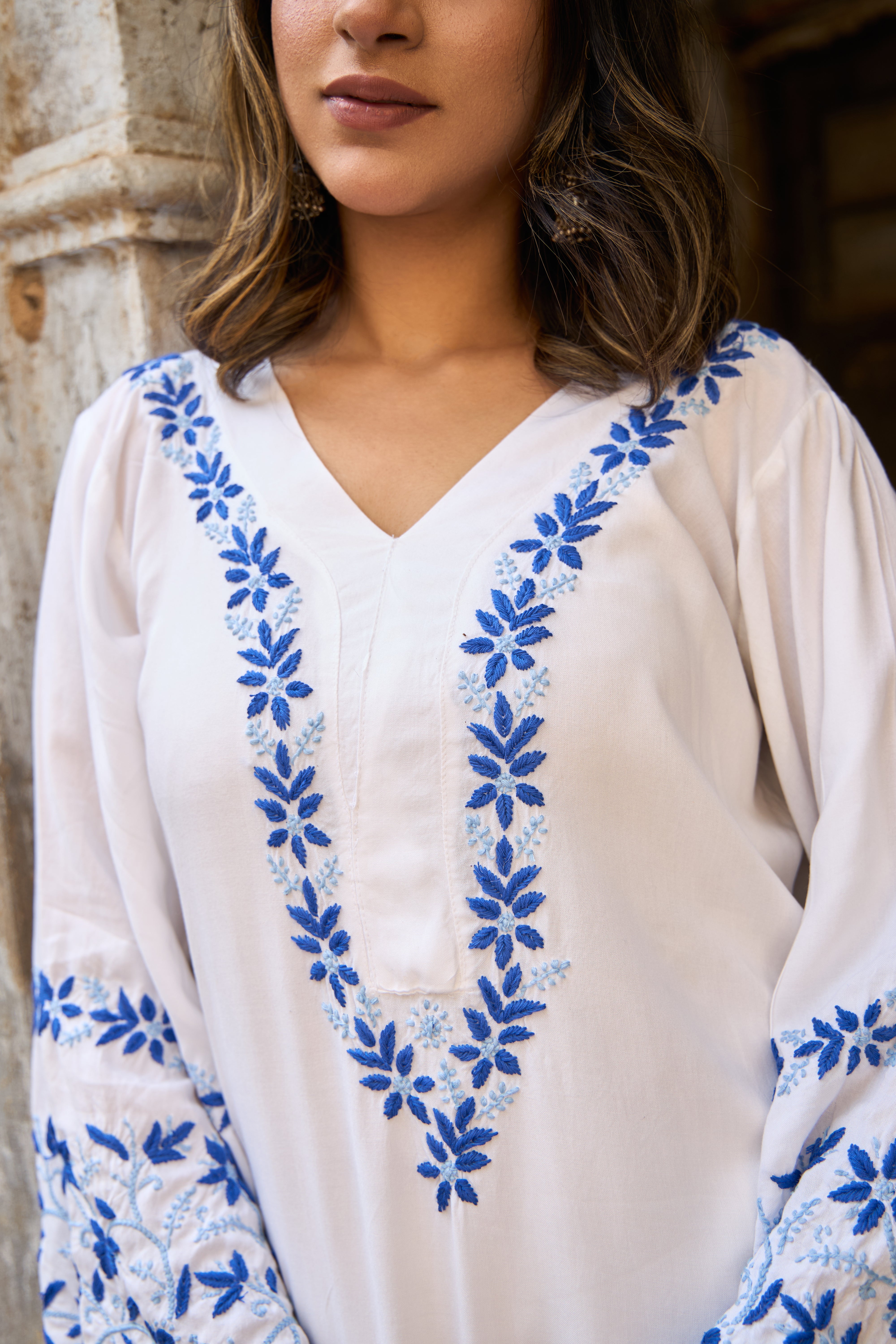 White Chikankari Kurta with blue floral embroidery worn by a person.