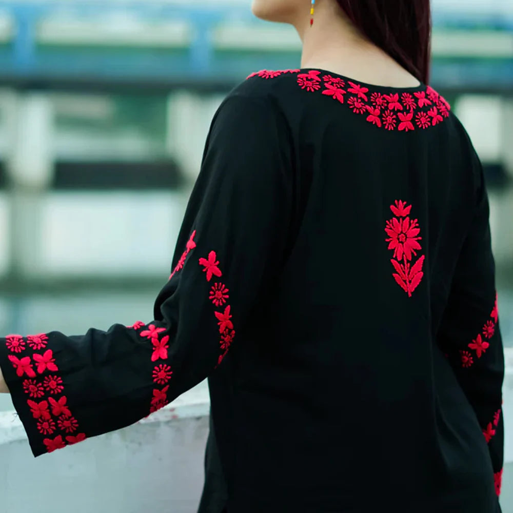 Black long-sleeve top with red floral embroidery on a blurred background