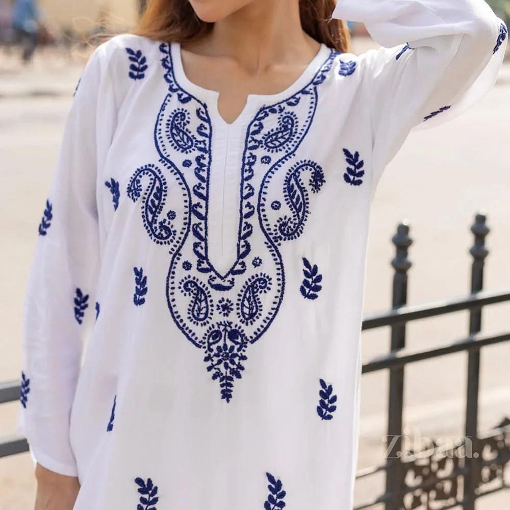 White blouse with blue embroidery worn by a person outdoors.