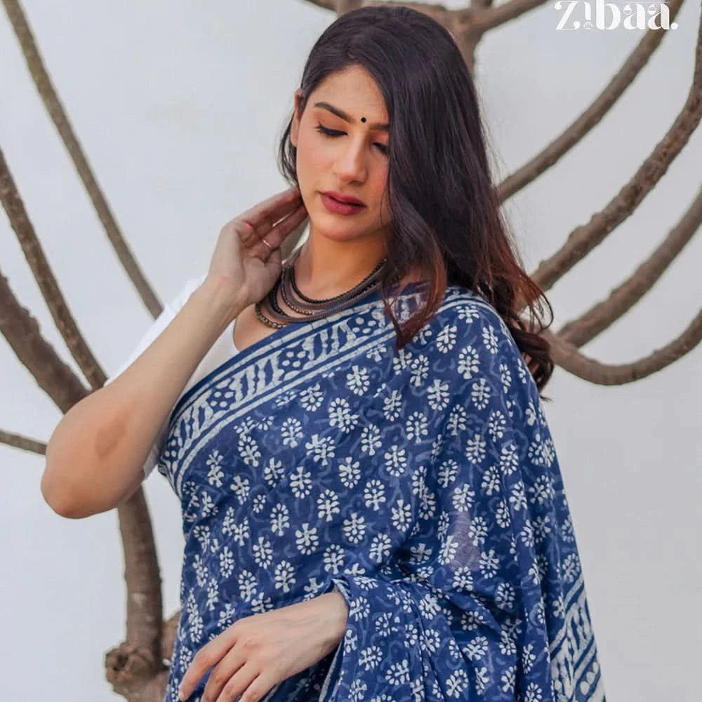 Woman wearing a blue and white patterned saree with a neutral background