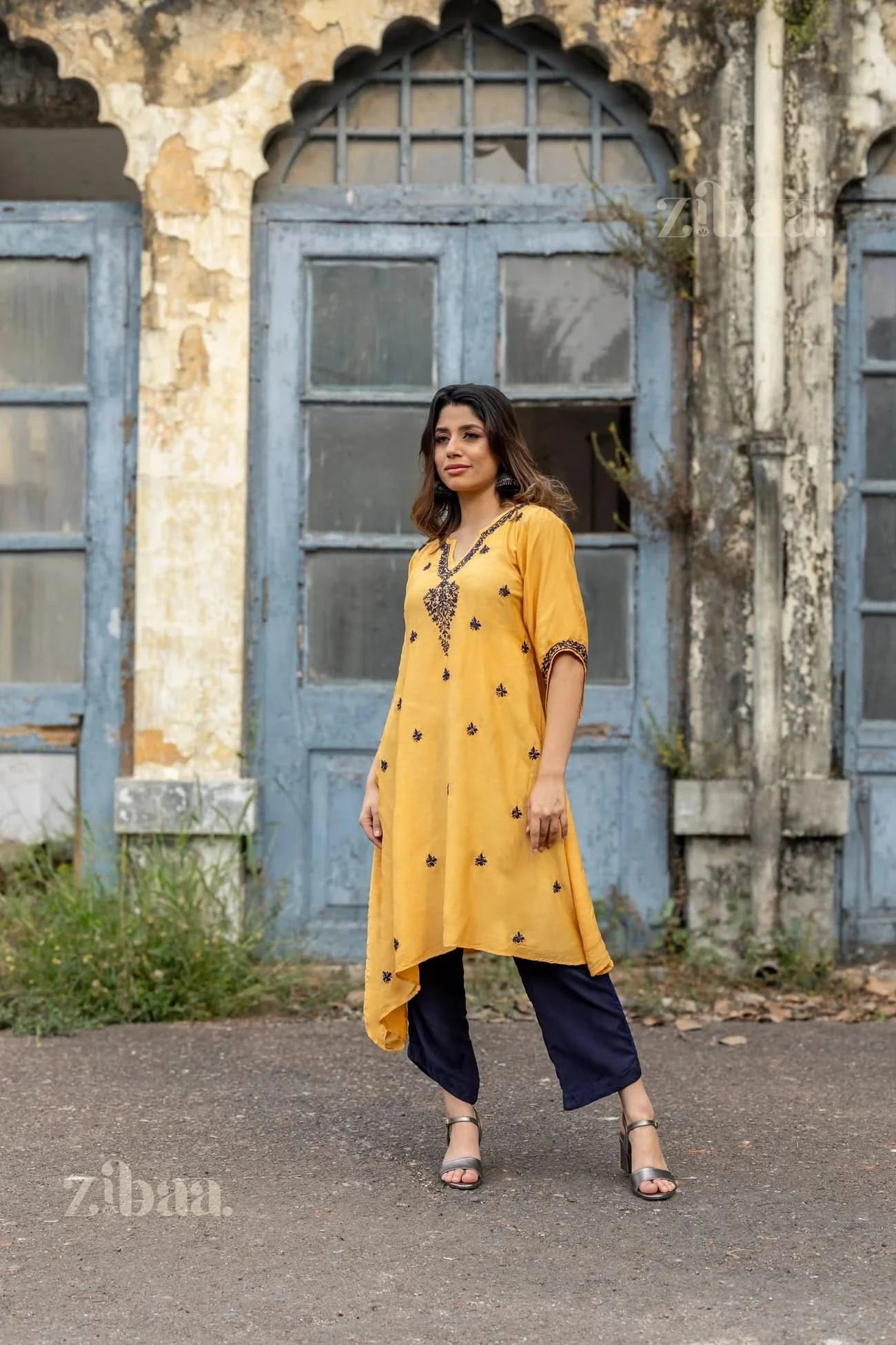 A woman poses outdoors in a mustard Chikankari Kurta Set paired with navy palazzos, exuding timeless elegance with intricate embroidery.