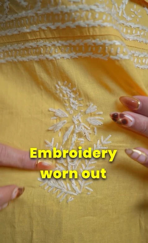 Yellow fabric with worn-out embroidery and hands holding it