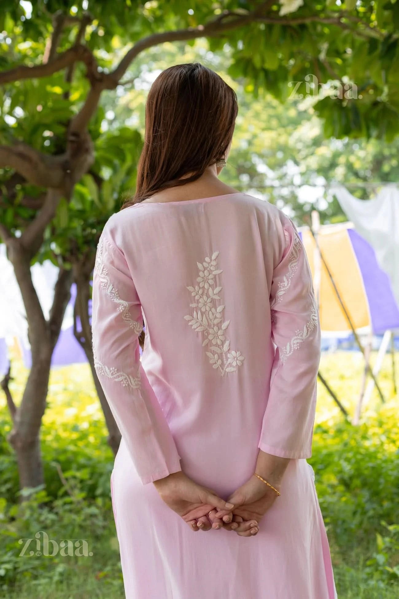 Back view of a Pink Chikankari Kurti with delicate white embroidery, showcasing traditional elegance in a lush outdoor setting.
