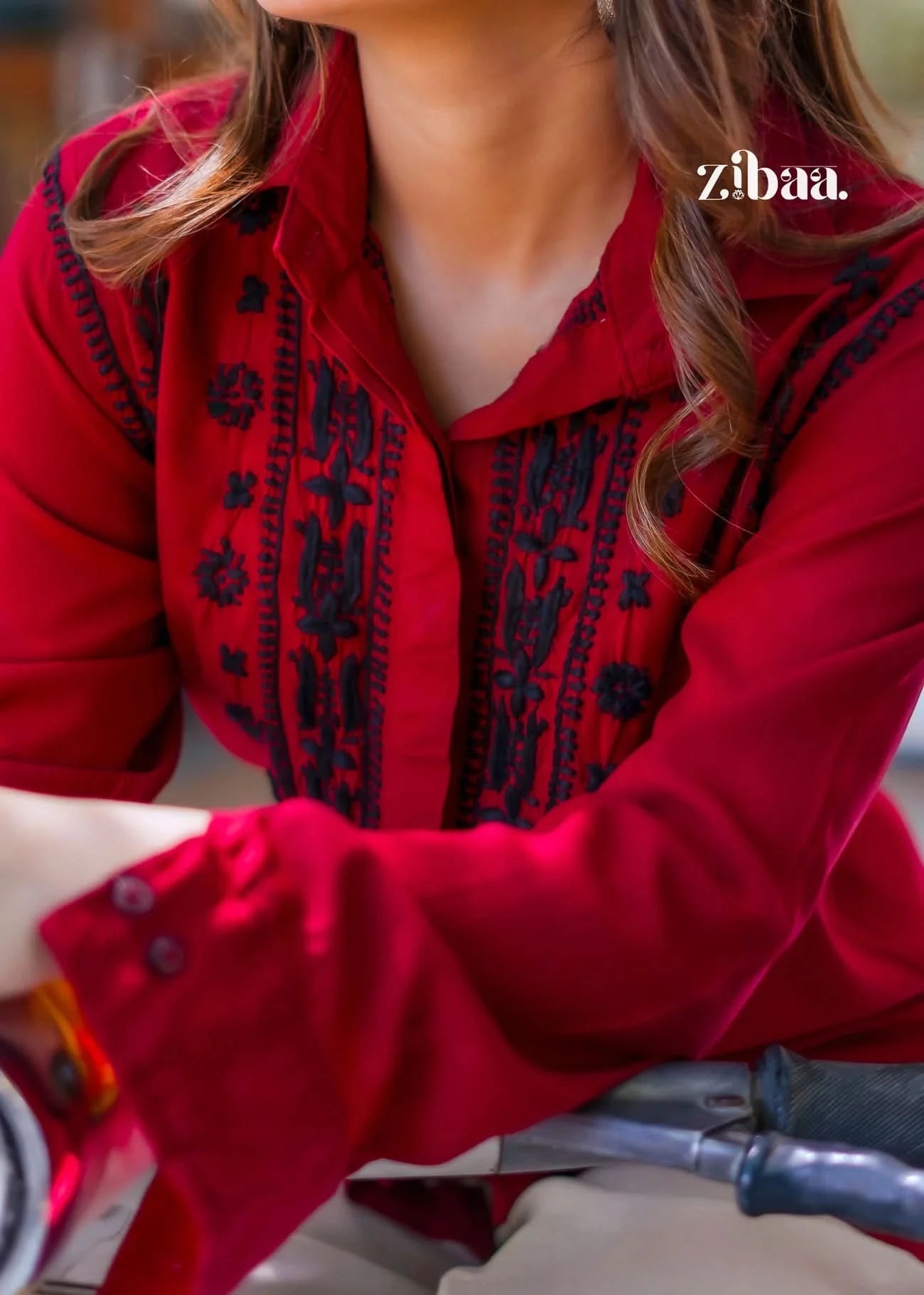 The close-up brings out the detailed black embroidery on the red chikankari shirt, emphasizing its elegant design.
