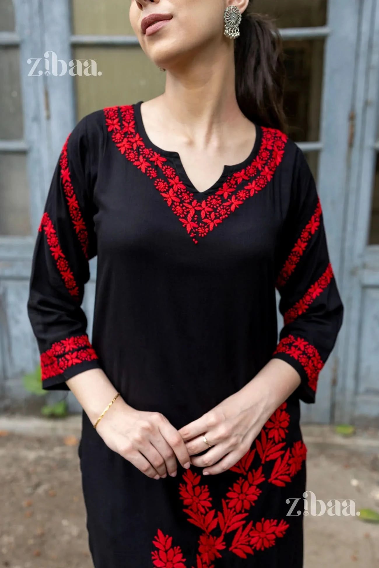 Black dress with red embroidery worn by a person, with 'zibaa' branding visible.