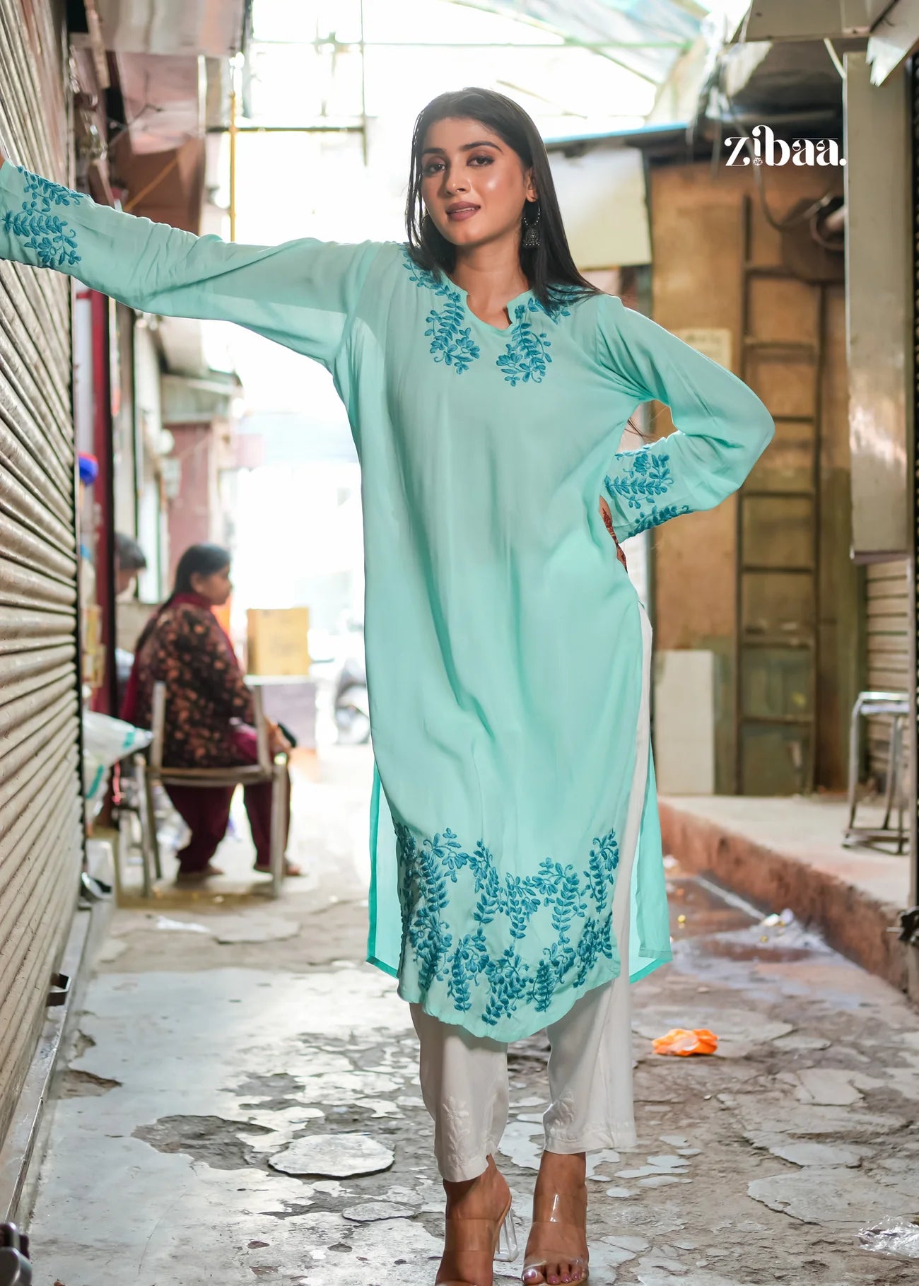 A woman looks graceful in a light blue chikankari kurti, standing on a street. The intricate embroidery highlights a blend of modern style and traditional craftsmanship
