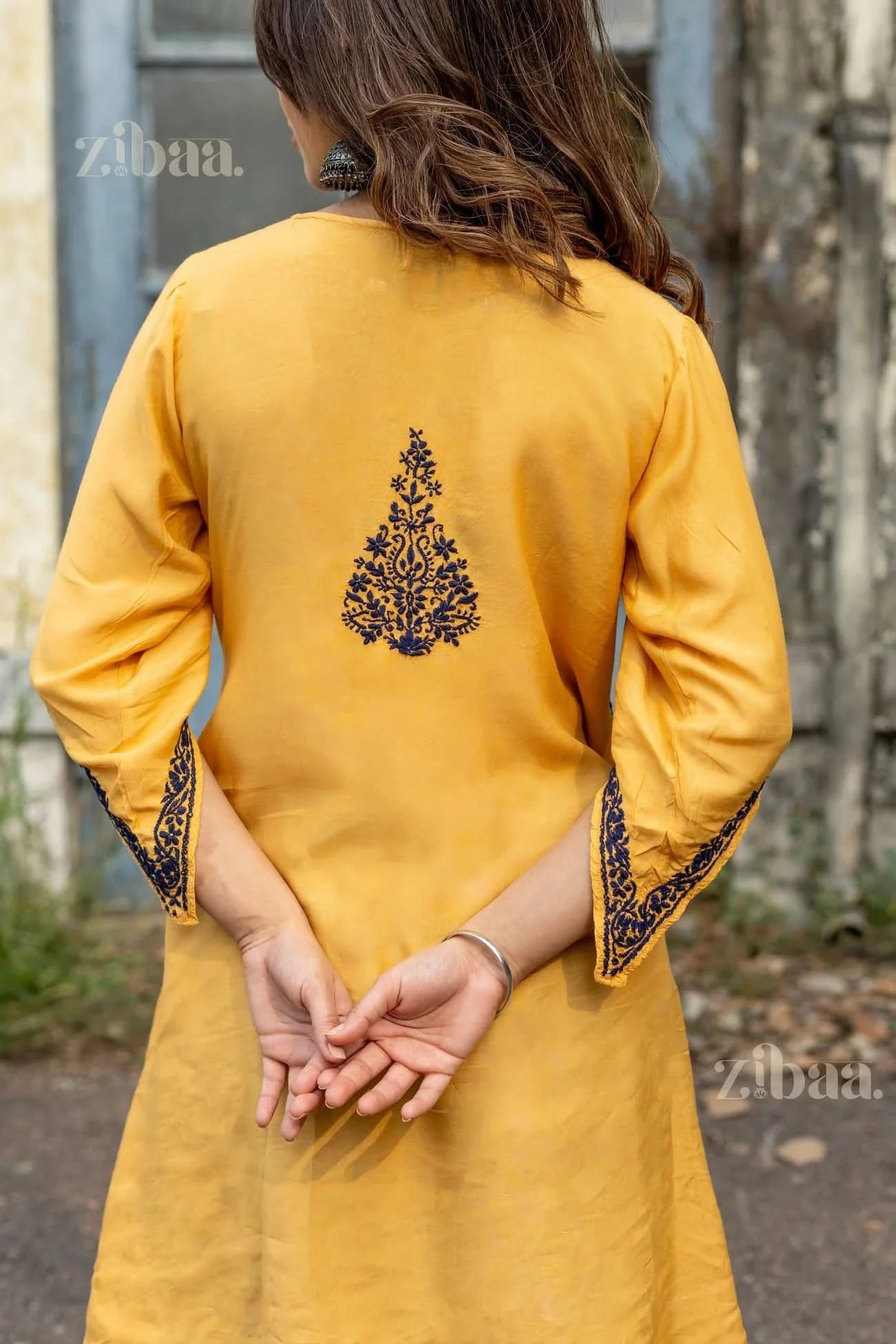 Rear view of a mustard Chikankari Kurta Set showing navy embroidery on the back and sleeves, highlighting traditional craftsmanship.