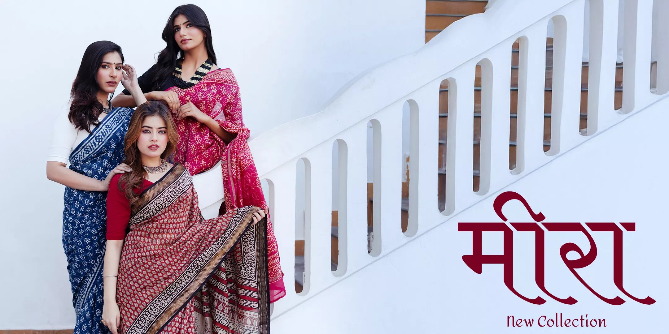 Three women in sarees on a staircase with text for a new collection.