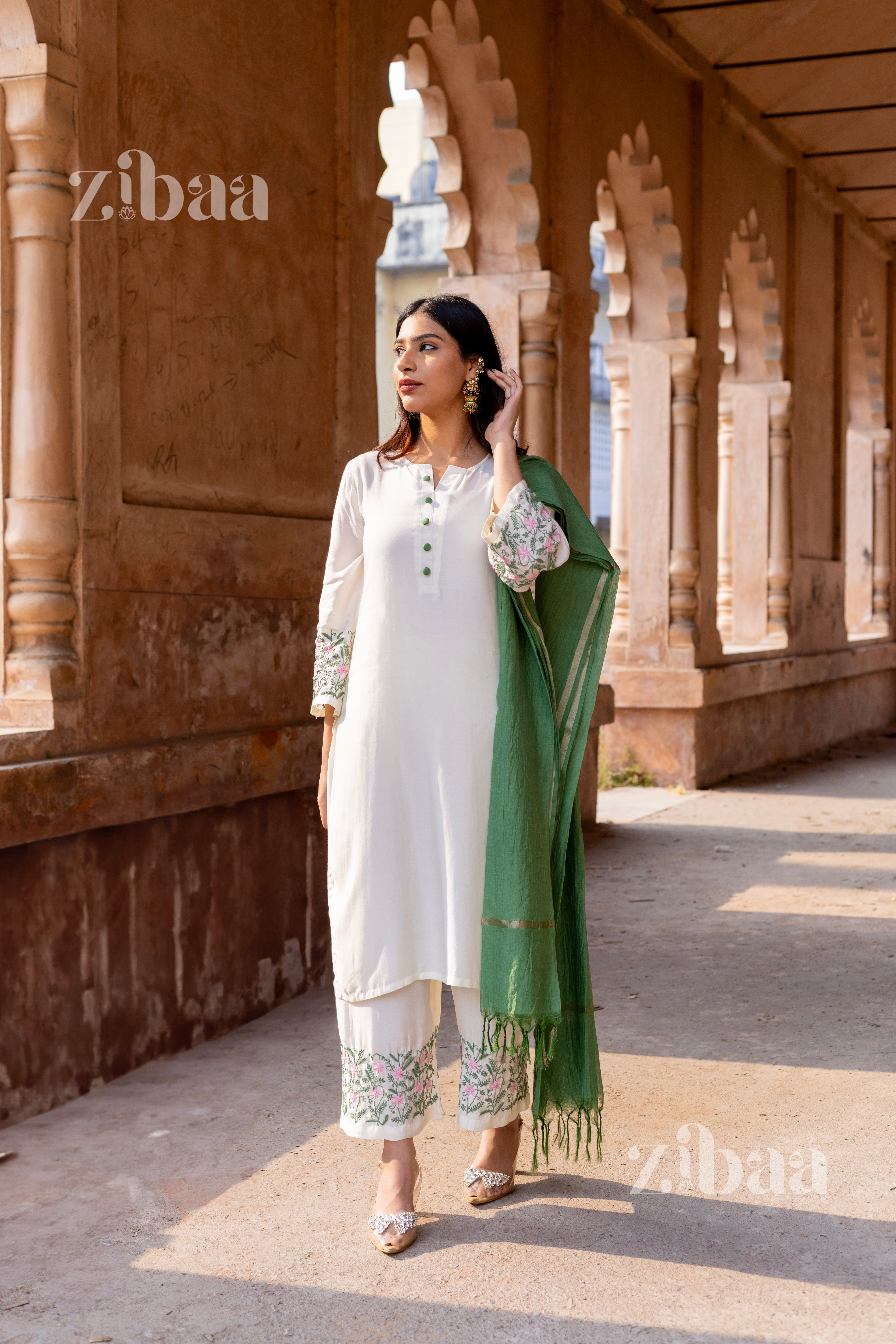 A woman wearing a traditional Husn Ivory Pure Muslin Chikankari Kurta Set with floral embroidery and a sage green mulmul dupatta.