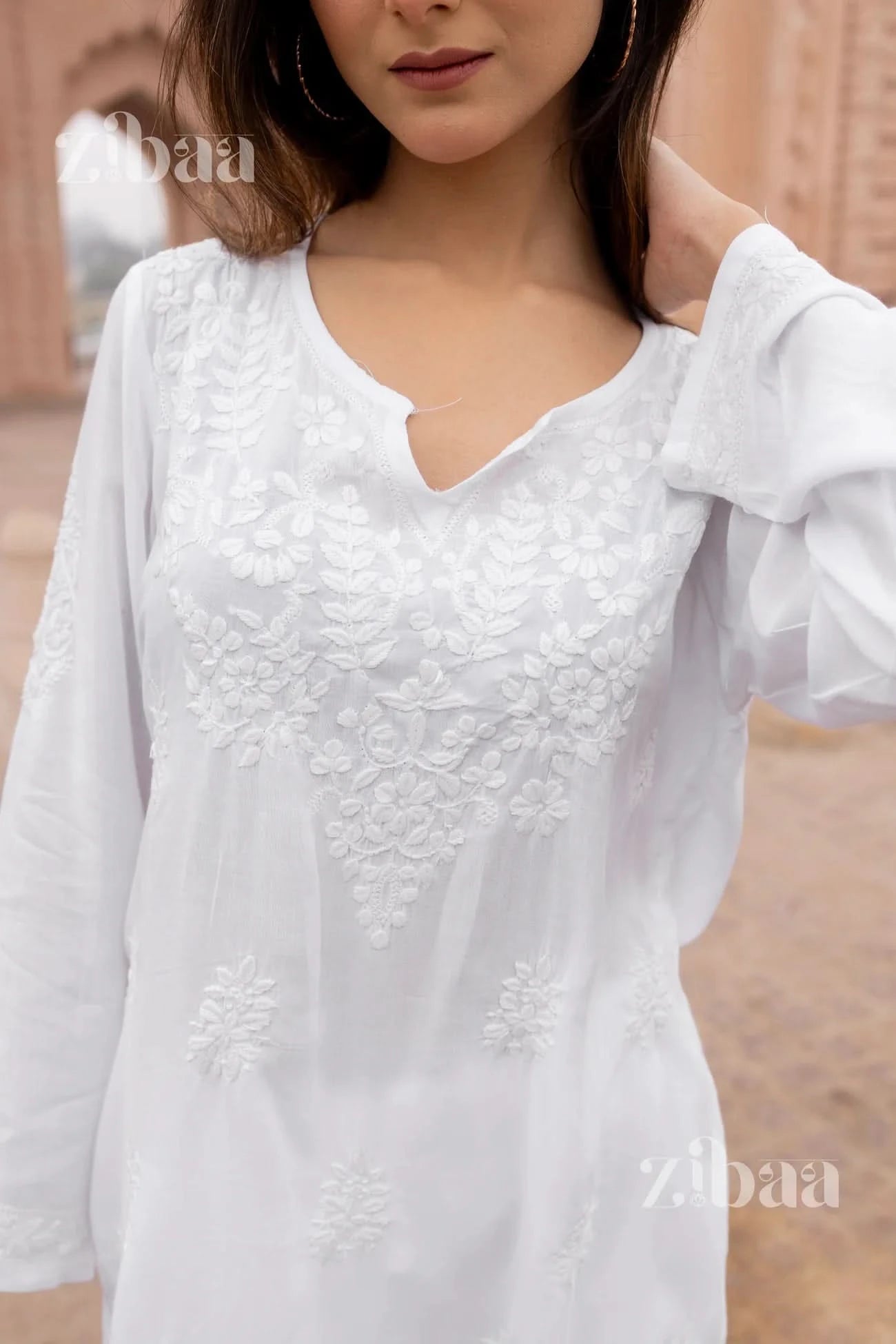 Effortless ethnic wear with a white short chikankari kurti, worn casually by a woman outdoors.