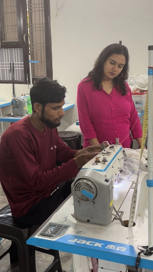 Two people working on a sewing machine in a workshop setting.