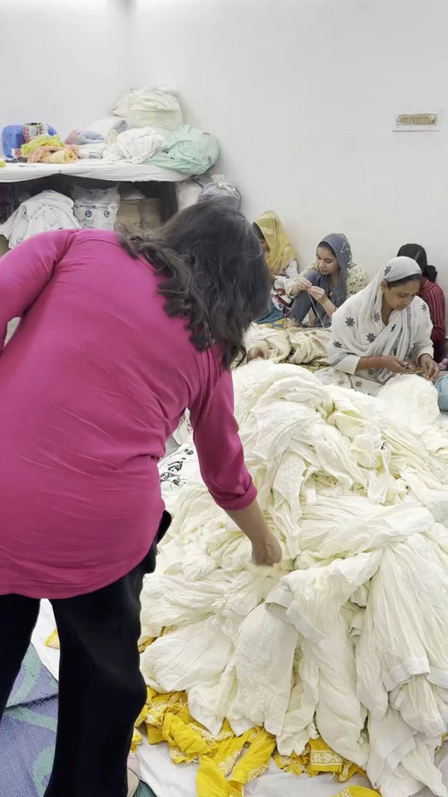 Person working with large quantities of white fabric in a factory setting